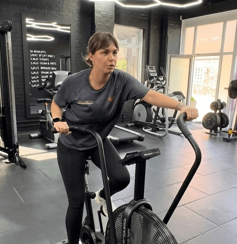Female personal trainer working out in a stationary cycling equipment.