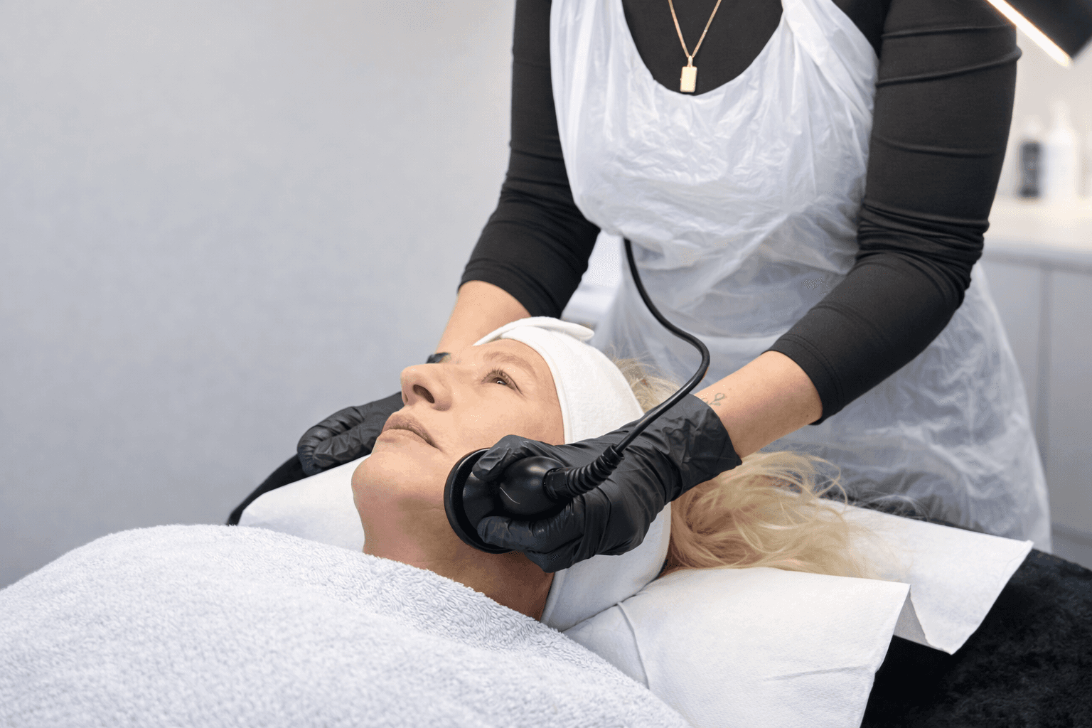 Client receiving a radiofrequency facial treatment to improve skin firmness in a professional clinic setting.