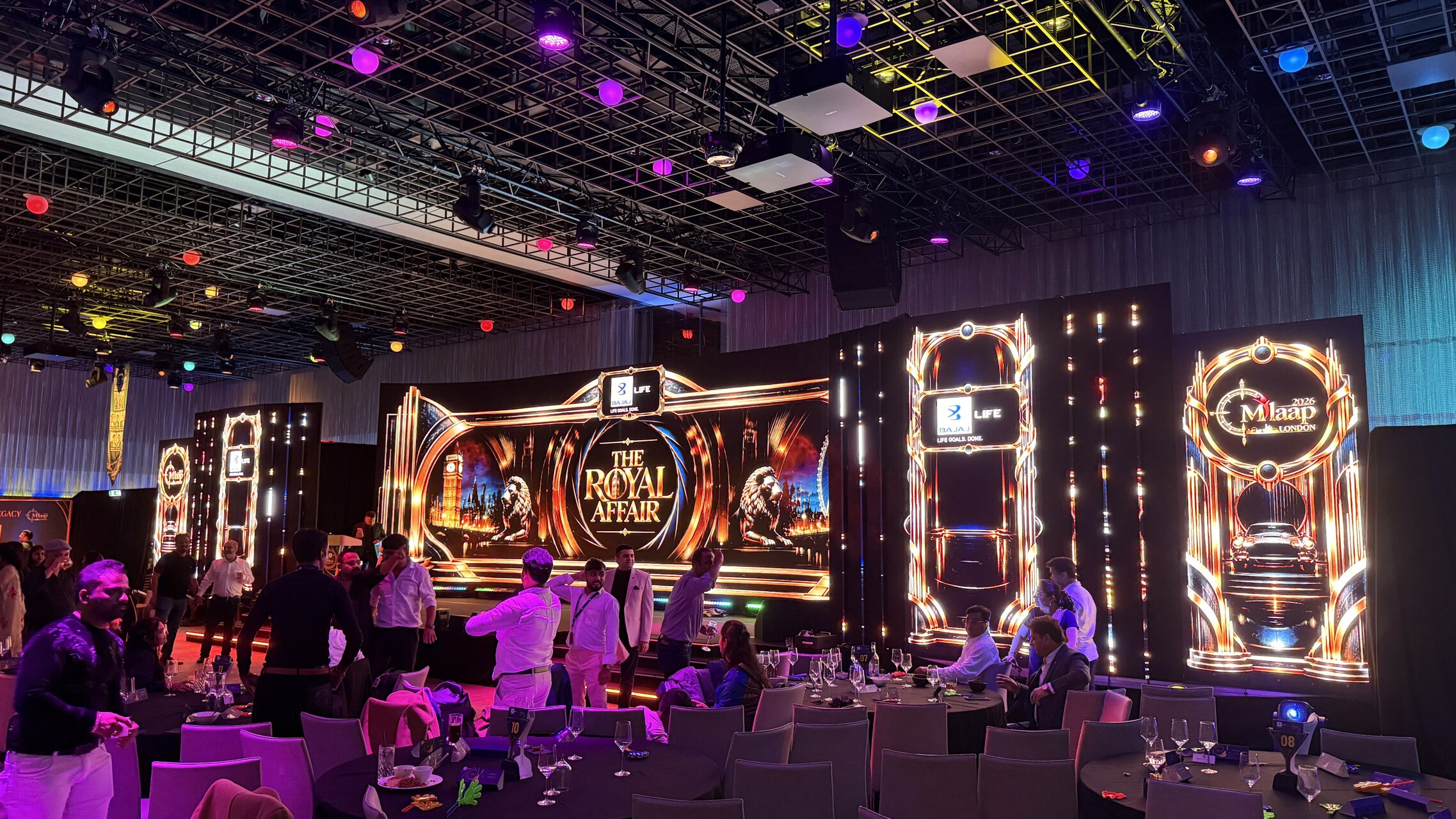 Angled view of The Royal Affair LED stage backdrop and outer video totems beside gala dinner tables.