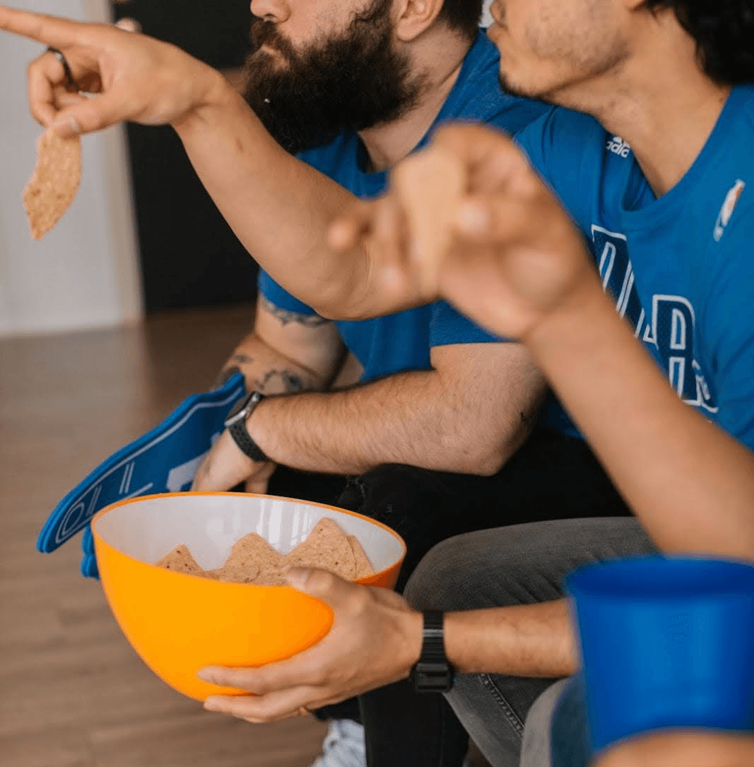 A lively gathering of people on the floor, indulging in chips while watching the Super Bowl.