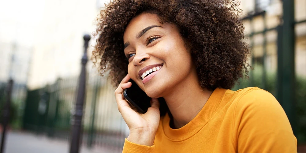 Happy african american young woman talking with cellphone in city