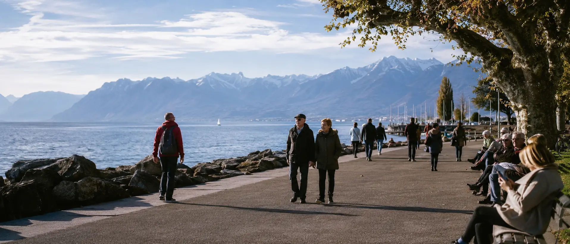 Genfersee-Promenade mit Spaziergängern, ruhigem Wasser und Alpen im Hintergrund