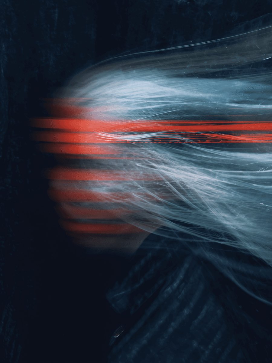 Abstract motion blur of white hair with red streaks on a dark background, creating a dynamic and artistic visual effect.