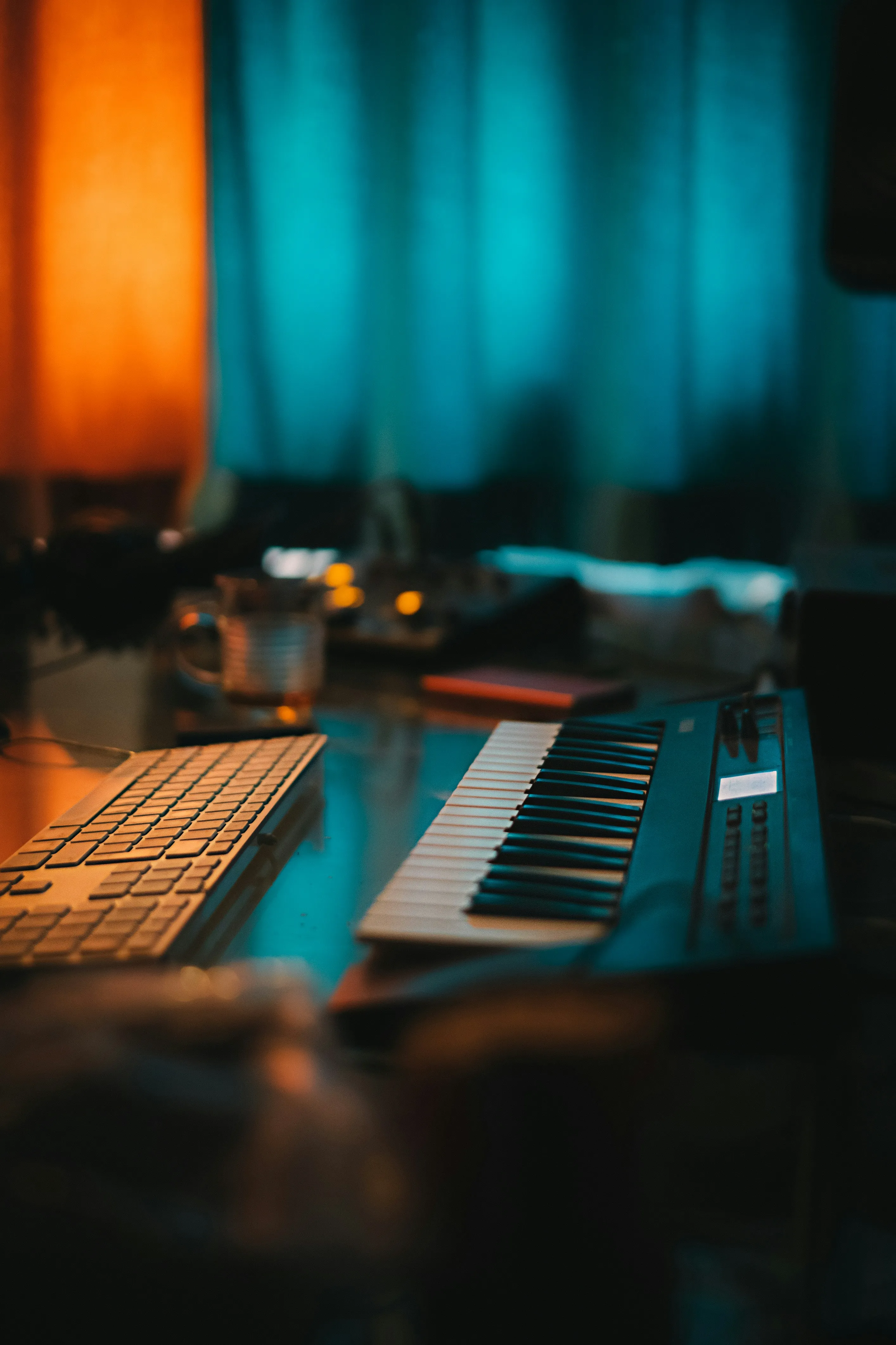 A music production service FAQ section with the title 'Music Production FAQ: Your Top Questions, Answered,' presented over a blurred background of a music studio keyboard and mixing equipment with warm and cool lighting. The section lists several common questions in expandable dark boxes."