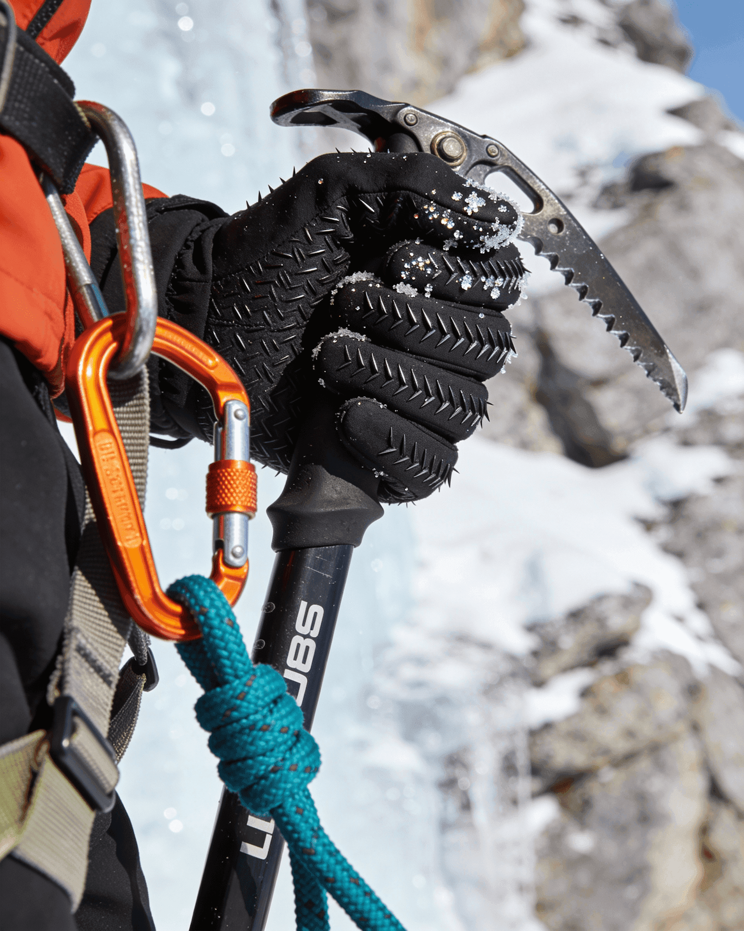 Ice climber gripping an ice axe with carabiners and rope