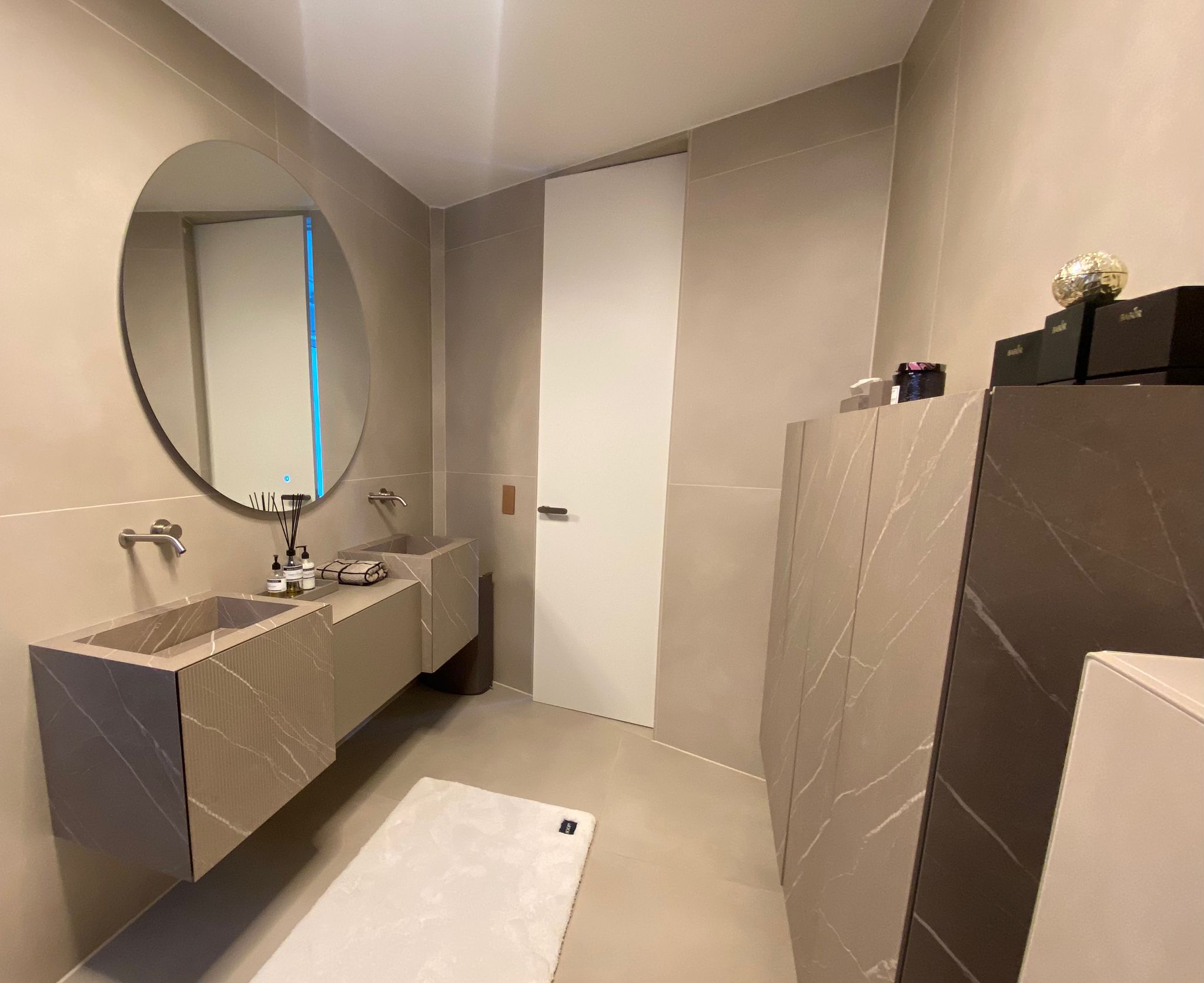 Spacious, luxurious living room with high ceilings, an elegant beige sectional sofa, warm ambient lighting, classical artwork, and rustic architectural elements, featuring an open layout with a view of a mezzanine level.