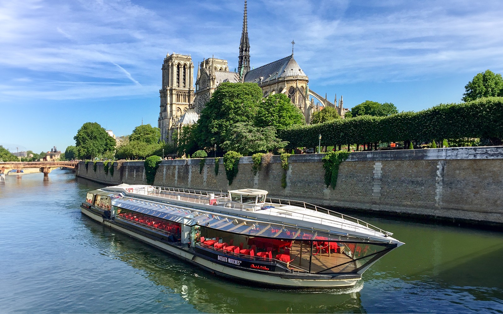 Tourists on Seine River cruise in Paris with view of Notre-Dame Cathedral.