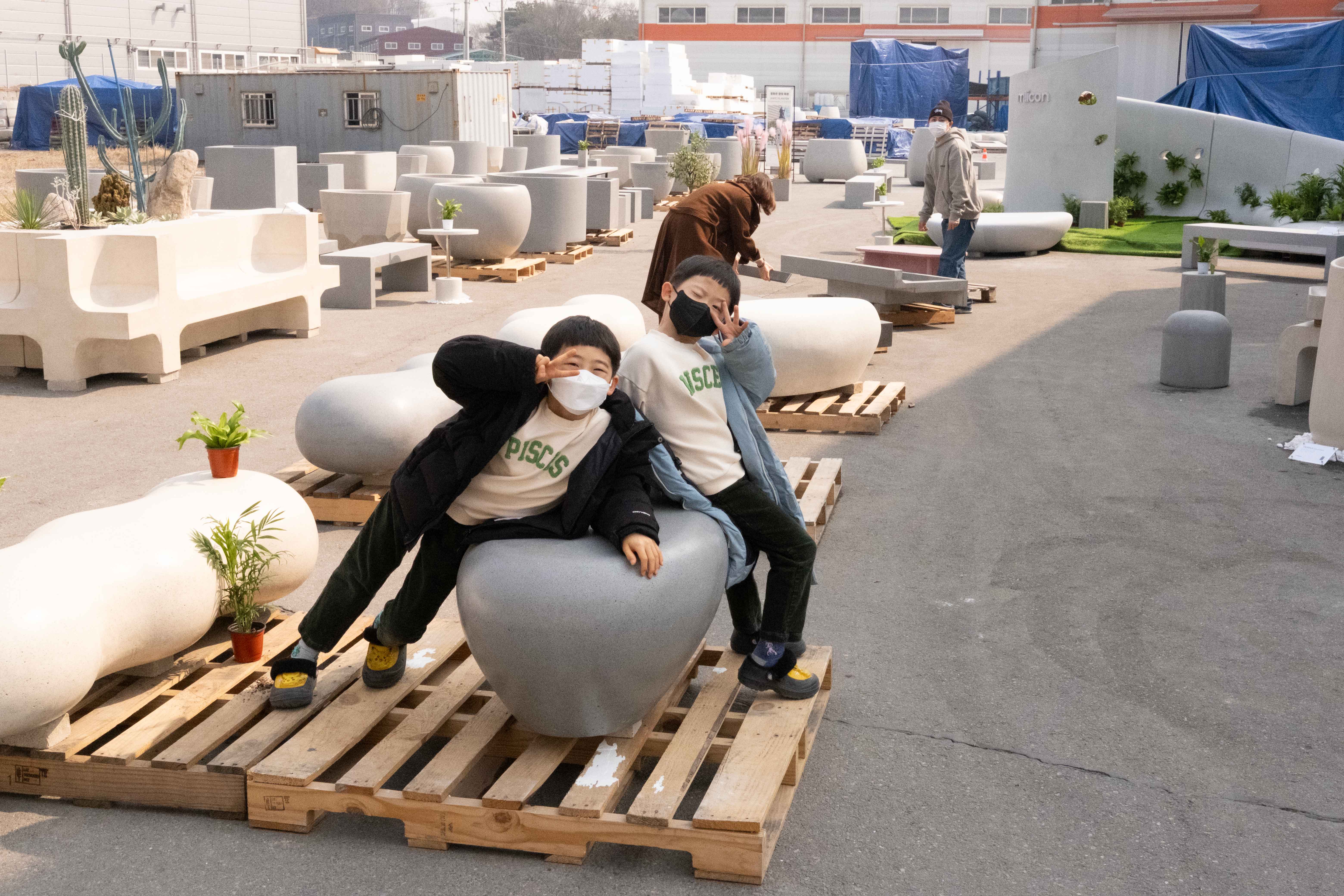 Monochrome fashion editorial of a model in an oversized white trench coat walking in profile on a high-key background.