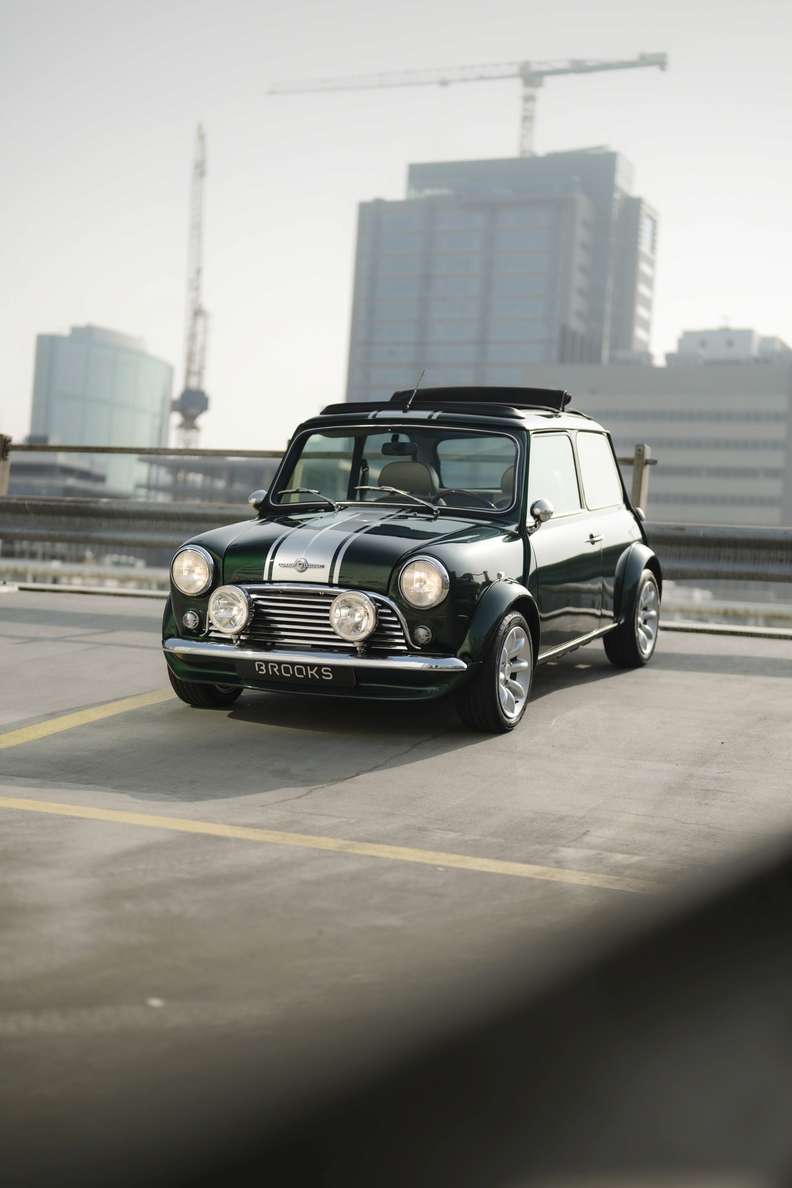A classic mini car parked on an urban rooftop with modern buildings in the background.