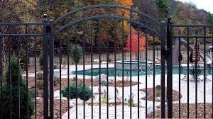 A black arched aluminum walk gate with a smooth top rail and internal spears, installed across a garden path.
