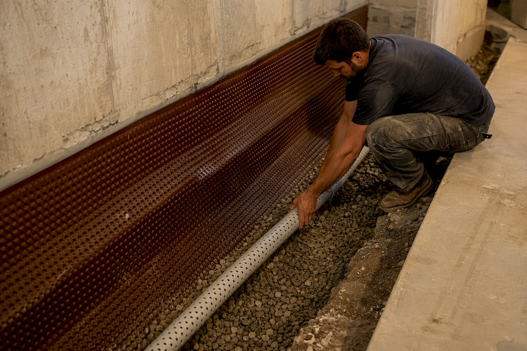 Perforated pipe installation in basement interior trench