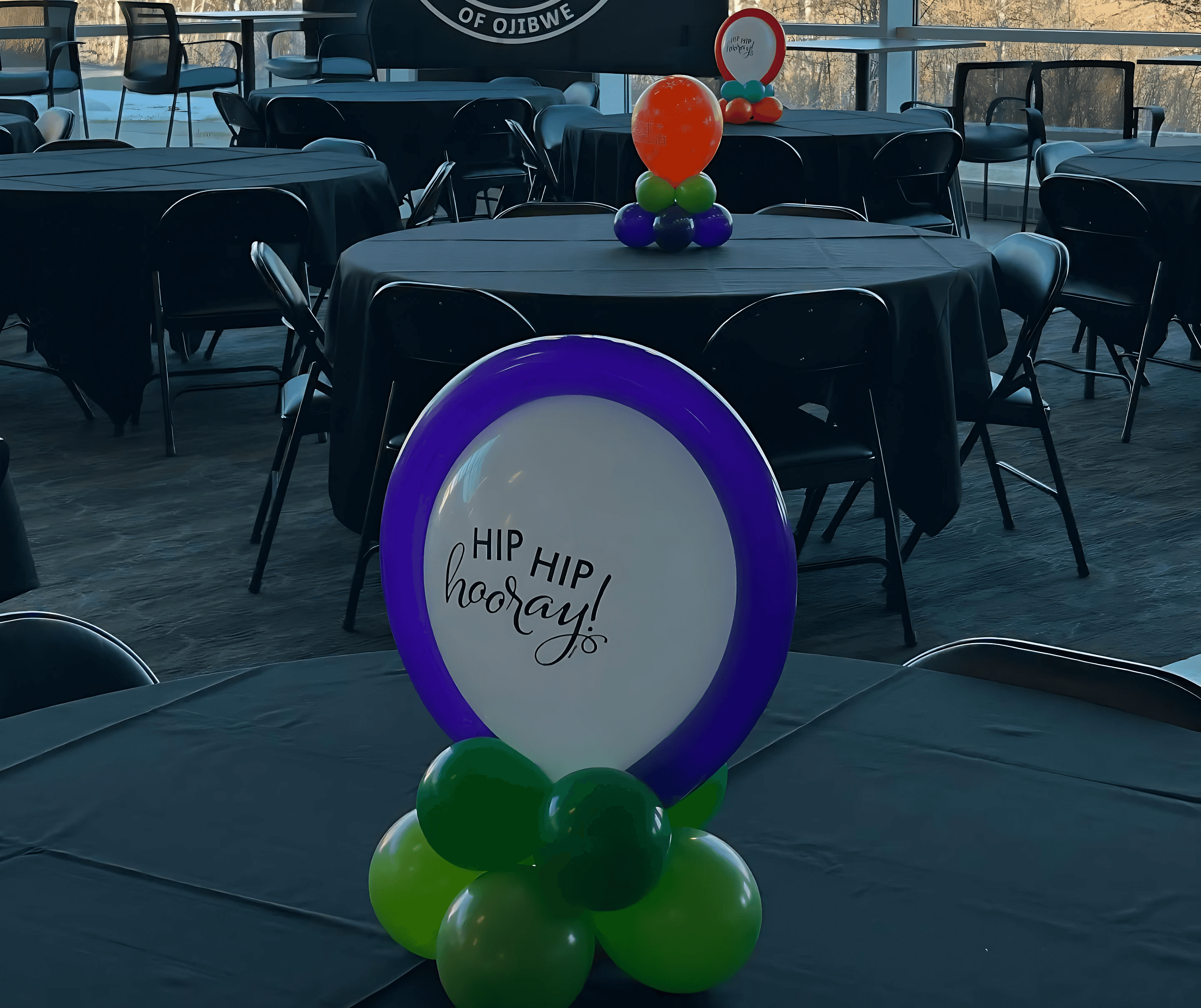 Purple and white balloon centerpiece with green base featuring the phrase Let’s Party created by Be Bold Balloons