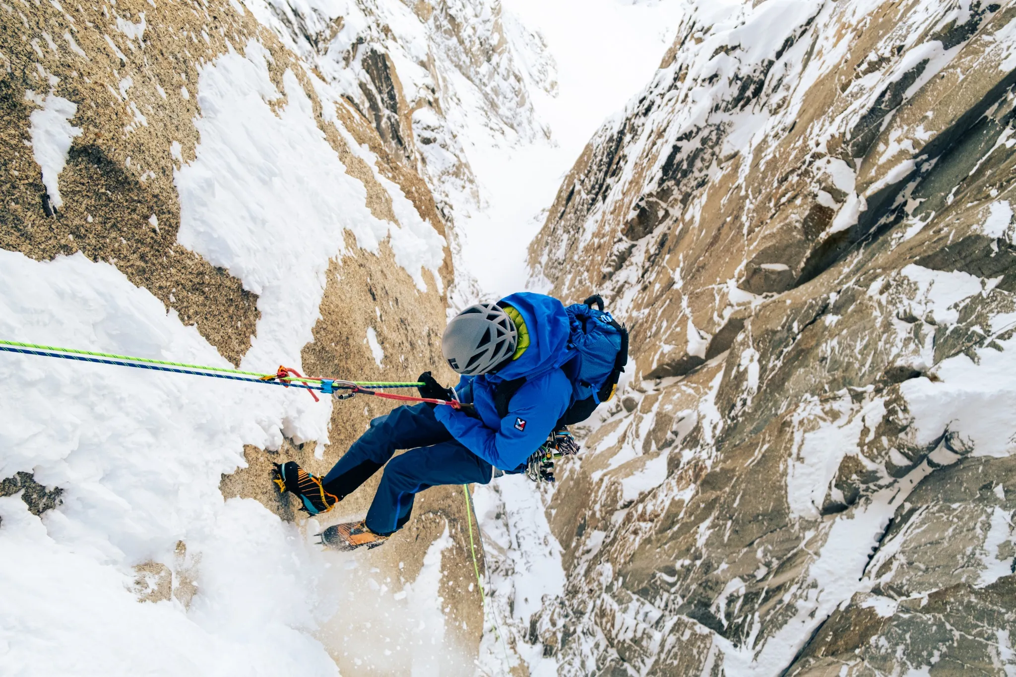 Grimpeur sur une paroi glacée, corde de sécurité visible, ambiance hivernale Millet.