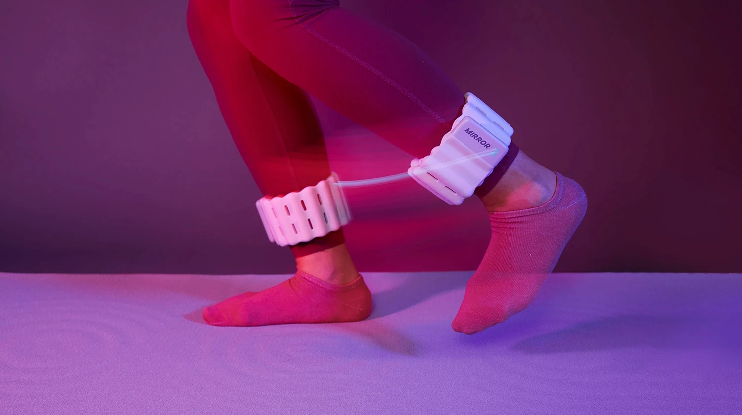 Person wearing white Mirror connected ankle weights while moving in purple lighting