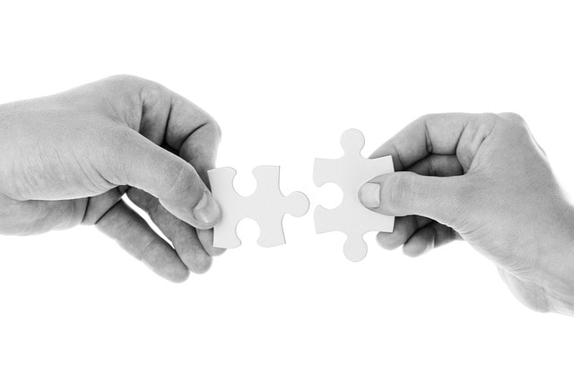 Two hands joining complementary puzzle pieces