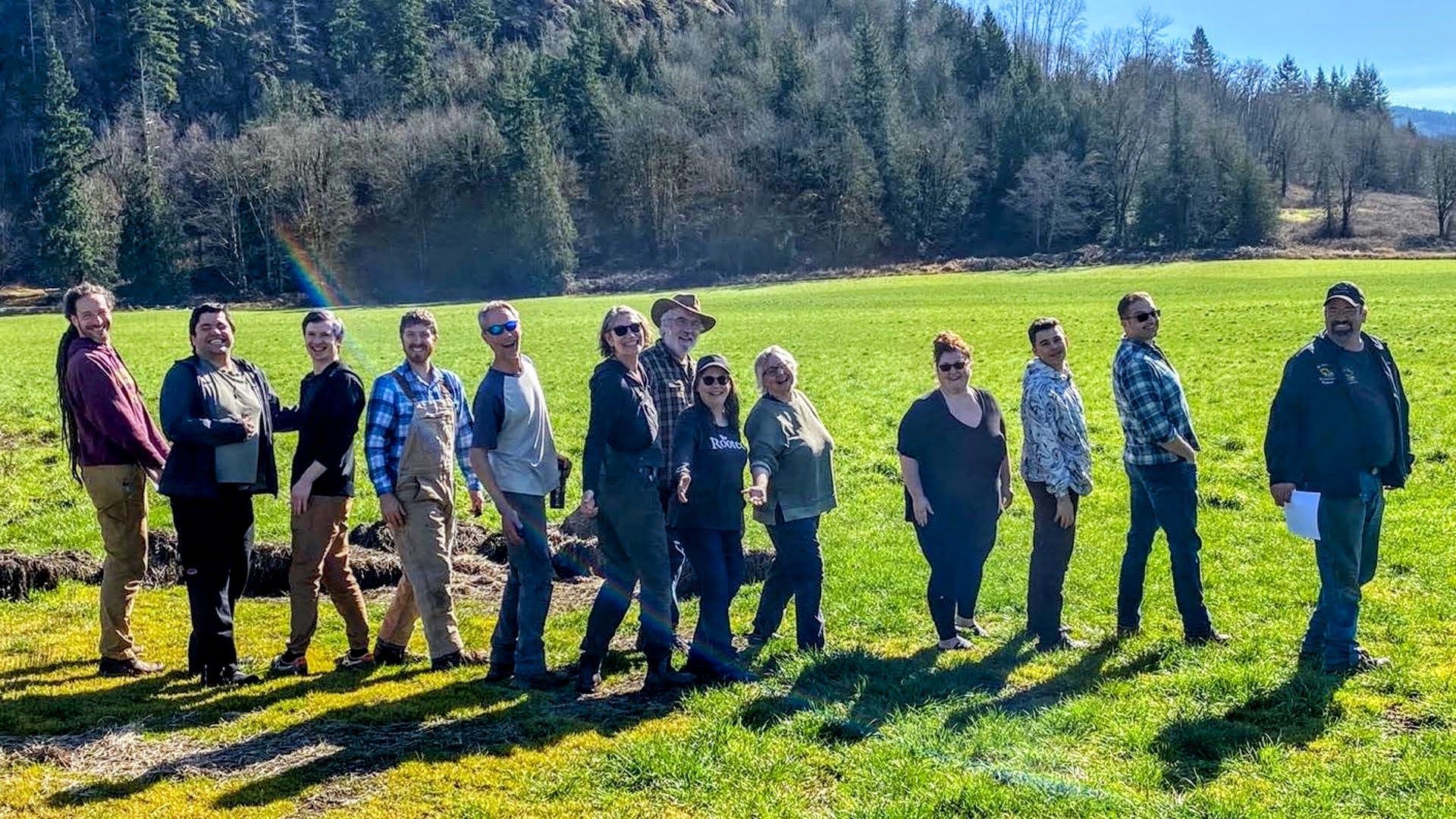 Rooted Northwest farmers and community members standing together in a green pasture on a sunny day
