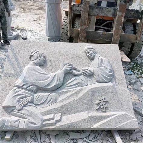 A grey stone carving depicting two ancient figures in traditional robes, part of a historical scene.