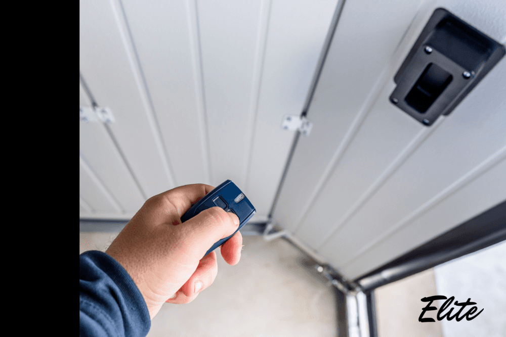 Hand holding a garage door remote inside the garage, showing secure opener use before holiday travel.