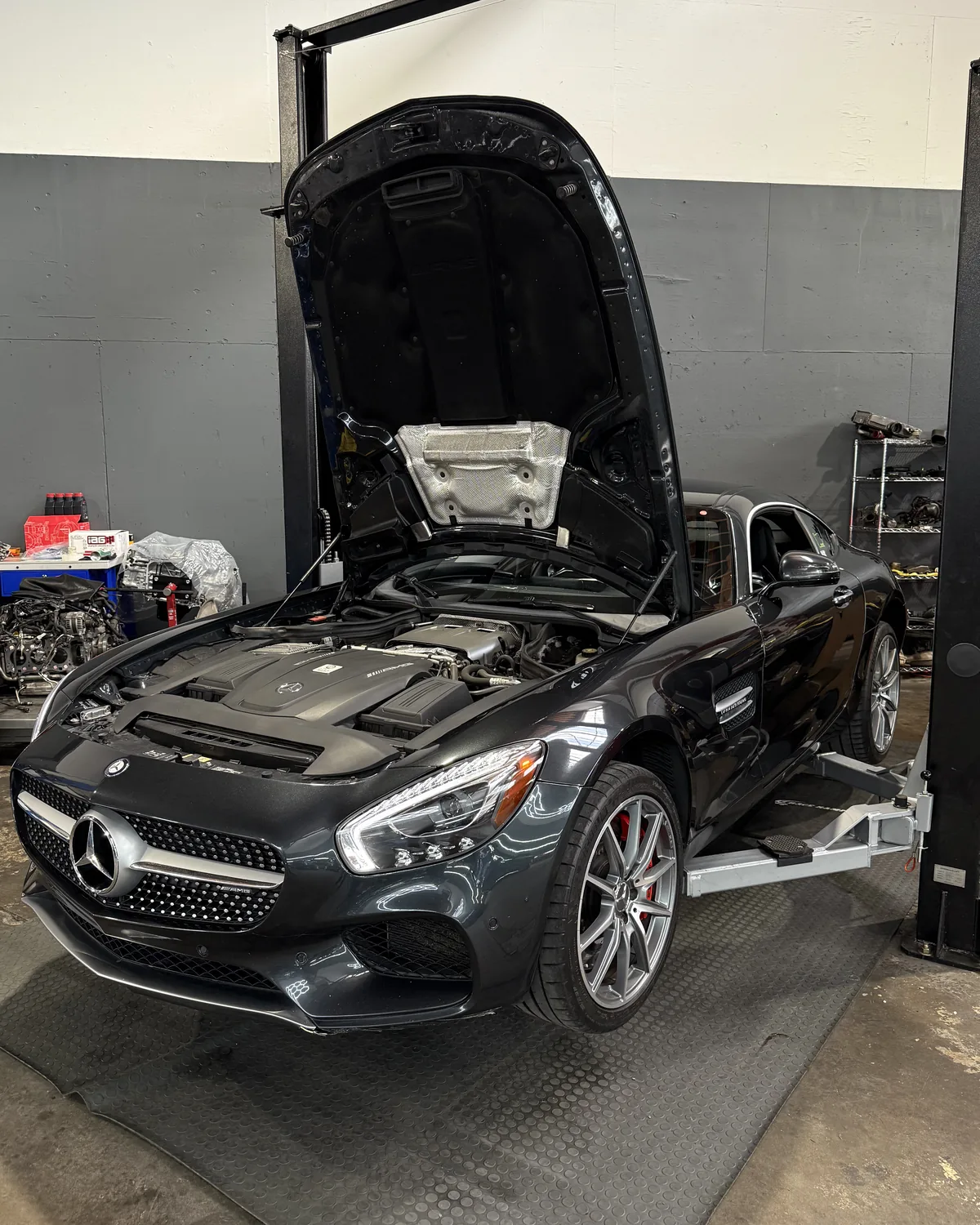 Black Mercedes-Benz coupe with its hood raised on a lift