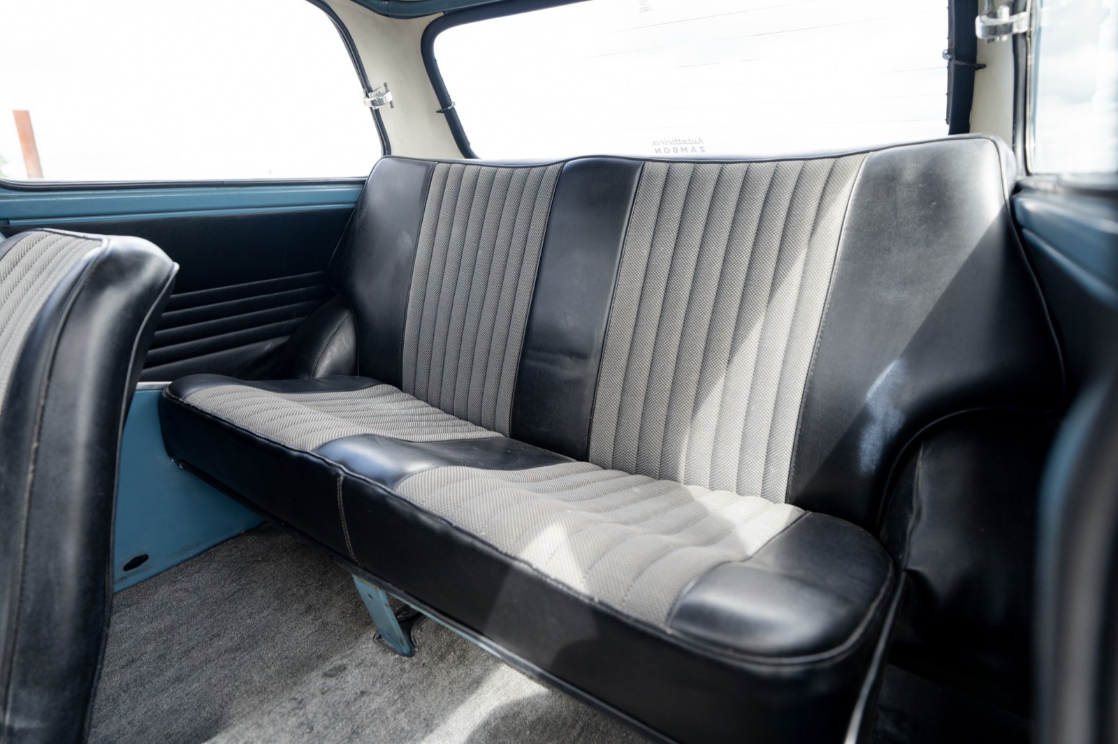 Interior view of a car's backseat, featuring gray upholstery and a spacious seating area. Natural light visible.