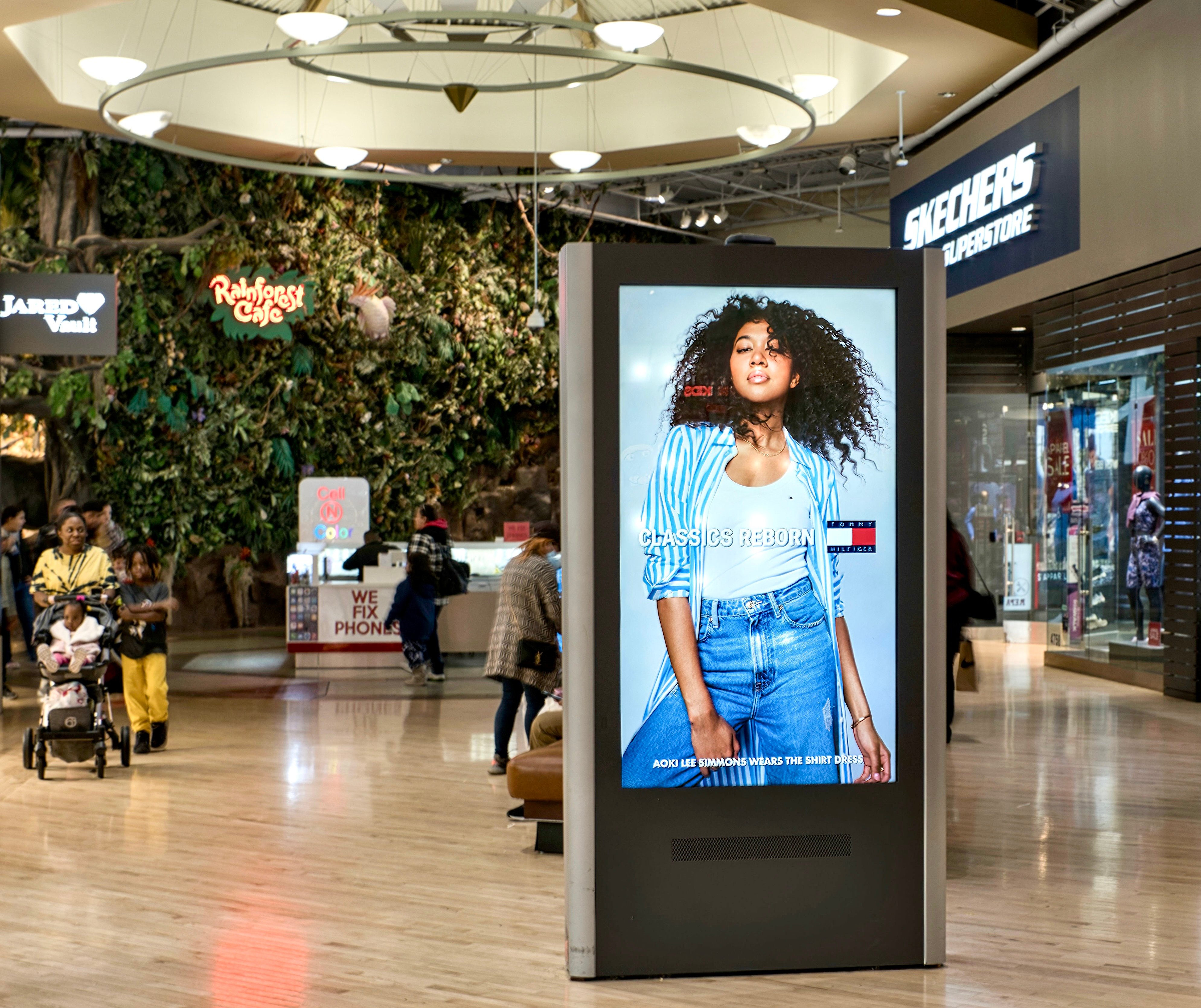 a man walking down a street past a large poster