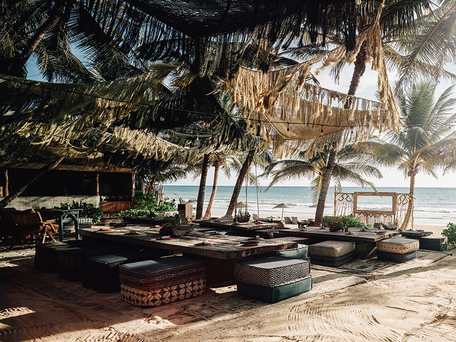 Group of people discussing their spiritual yoga journey on the beach at Nomade Holbox in Tulum Mexico, with a serene and peaceful atmosphere
