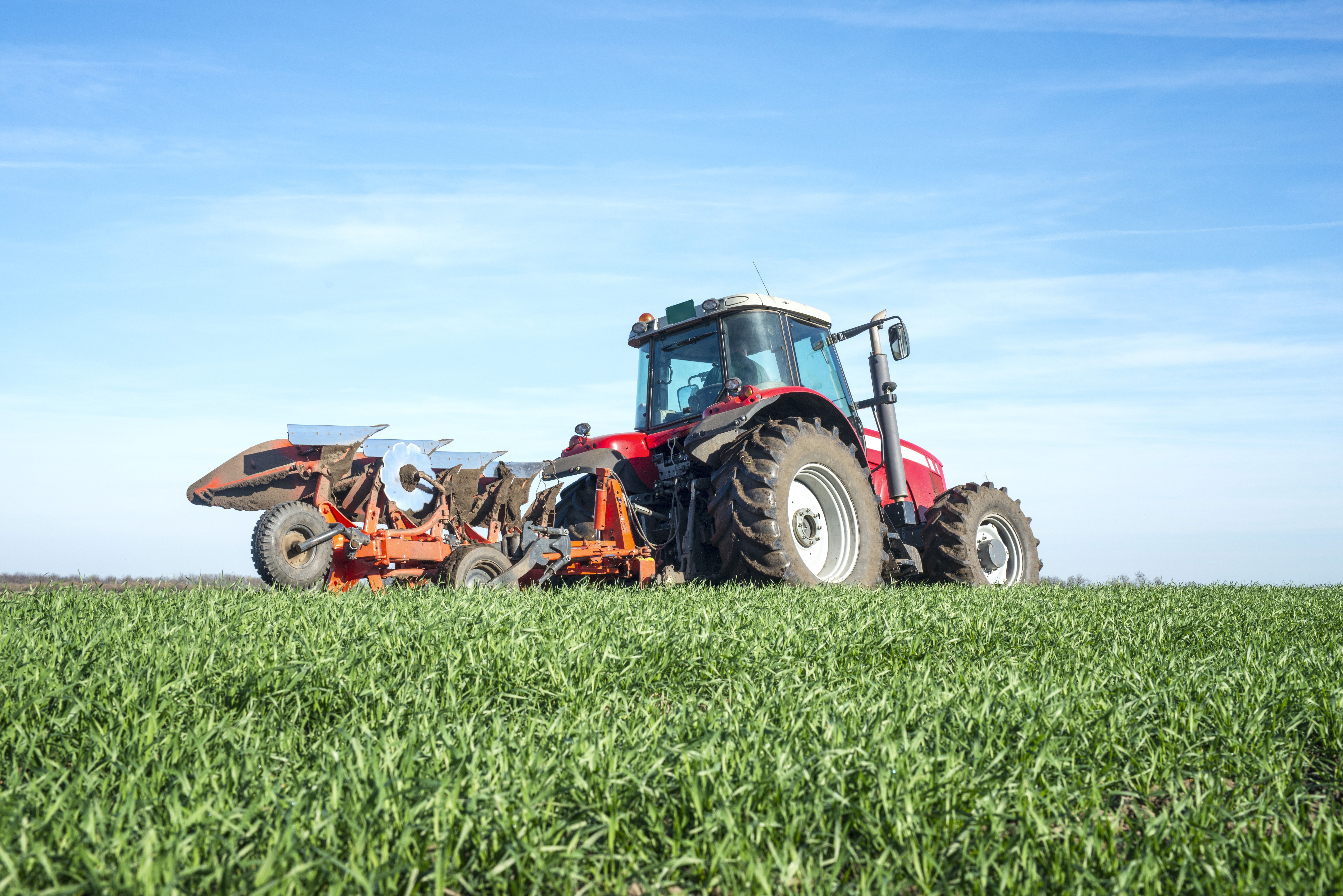 a red tractor parked on top of a lush green field