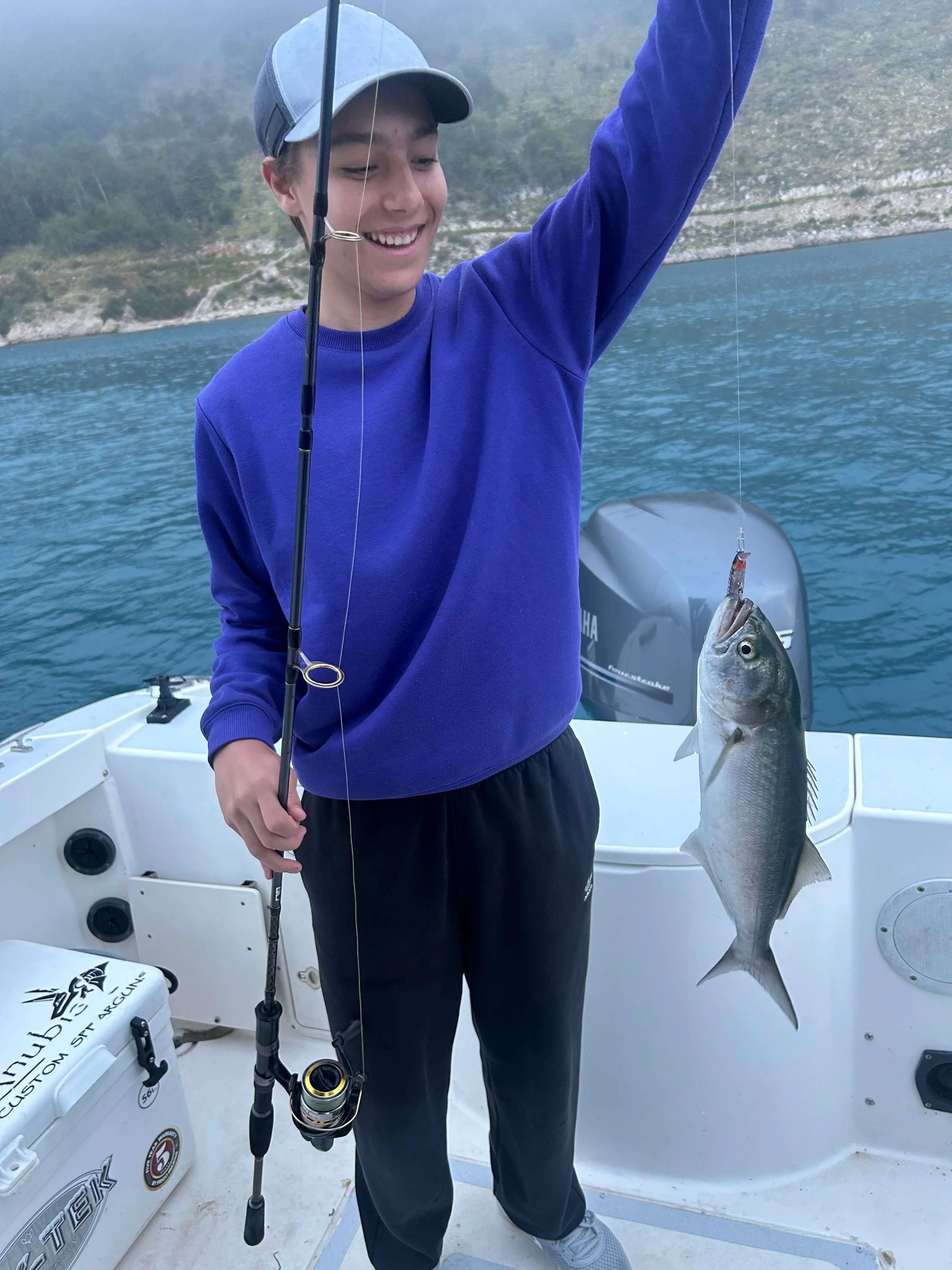 Child having fun catching fish during a family fishing trip on the Adriatic Sea.