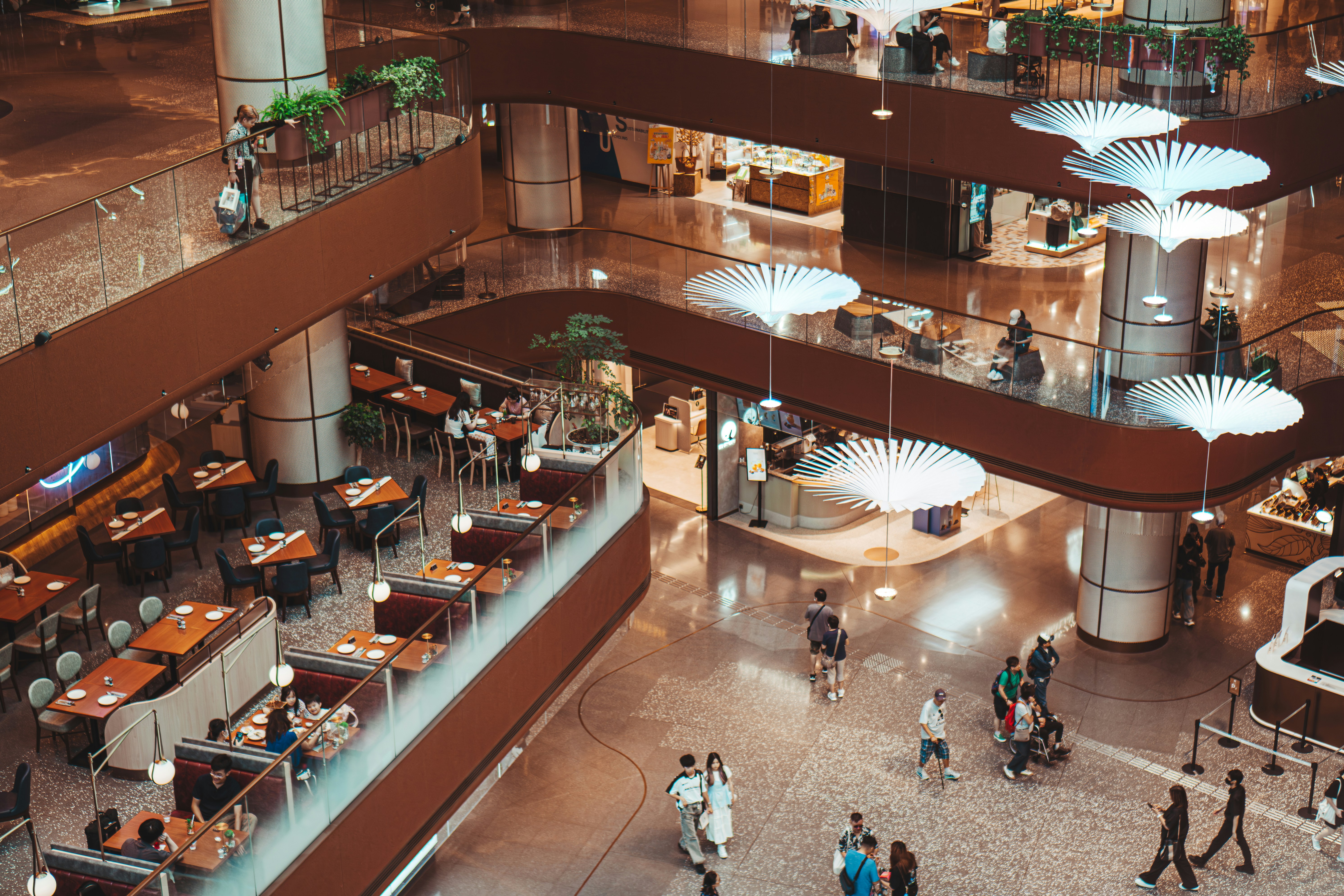 People walking and dining in a multi-level shopping mall.
