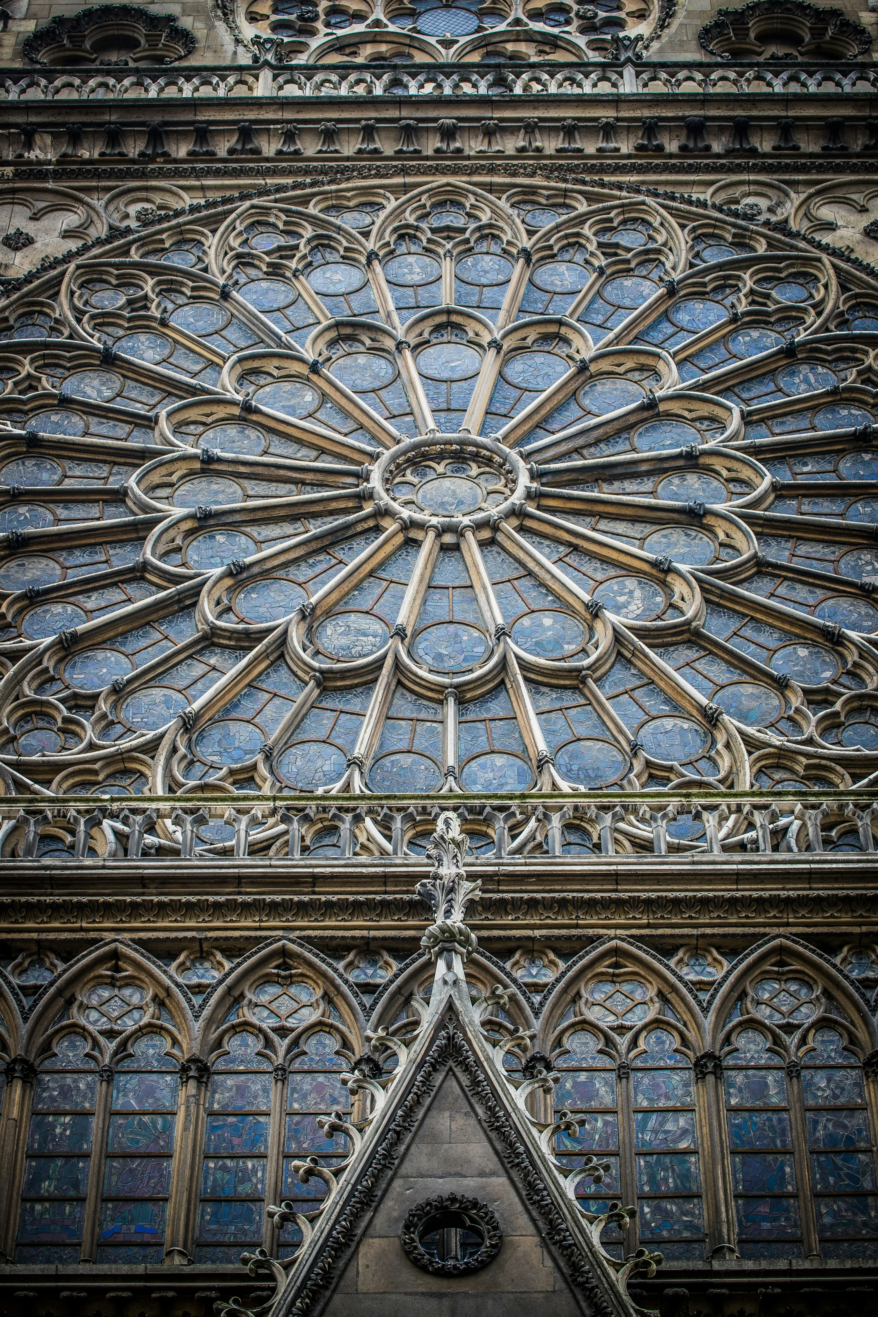 The closeup of one of Notre Dame's massive circular stained glass windows as seen from the outside looking up.