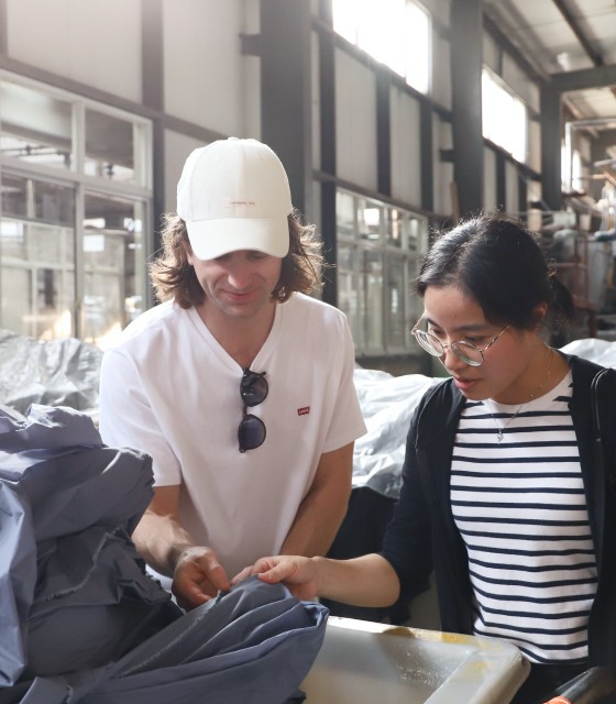 Founder of Sunday Superior at a factory looking at fabrics with production manager