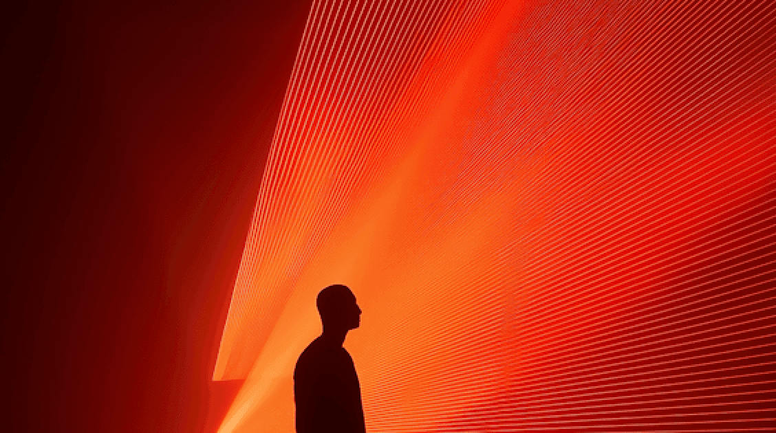 A man stands before a red light, suggesting he is halted at an intersection.