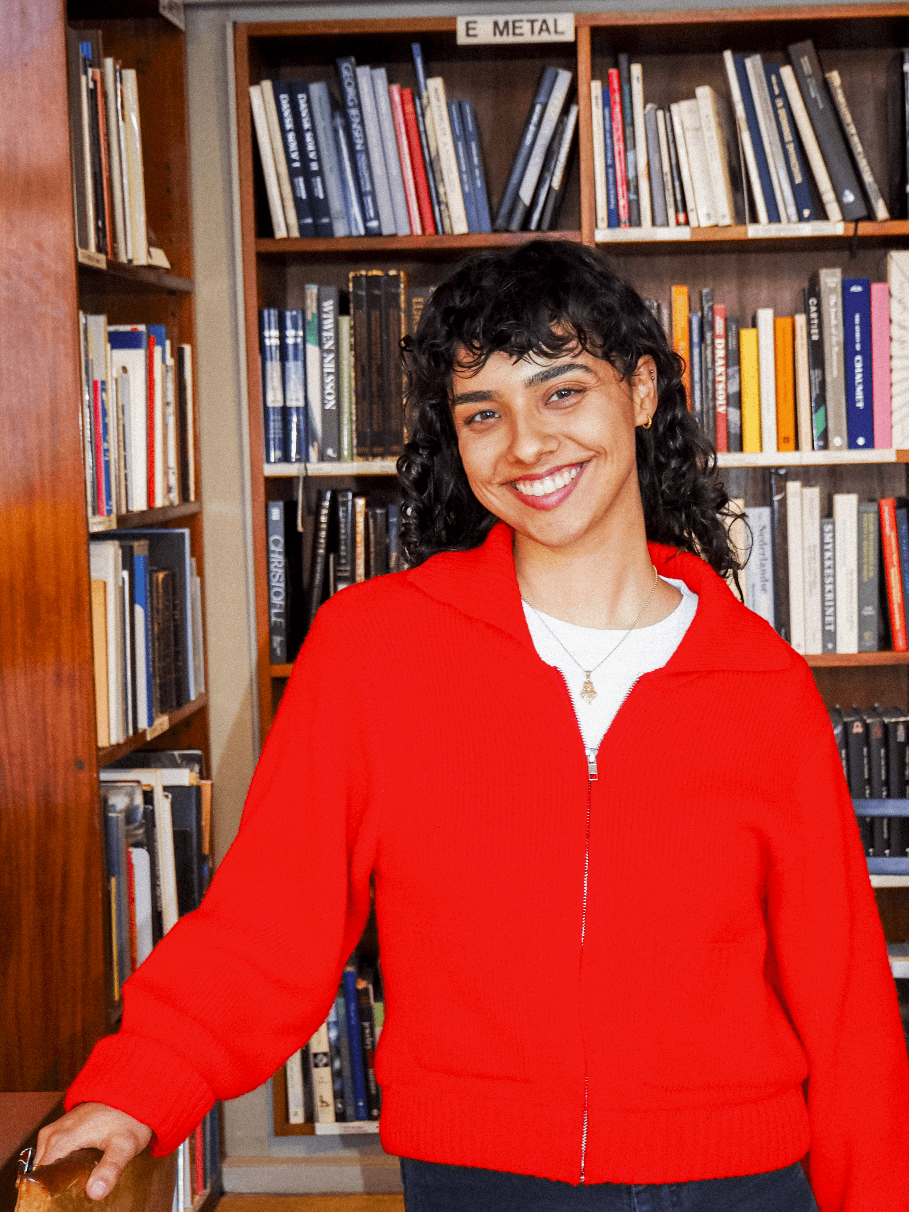 Maria smiling in front of books.
