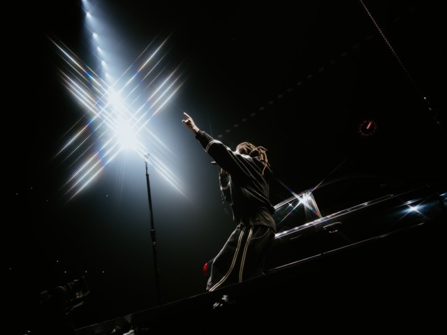 J. Cole performing under stage lights on The Fall-Off Tour