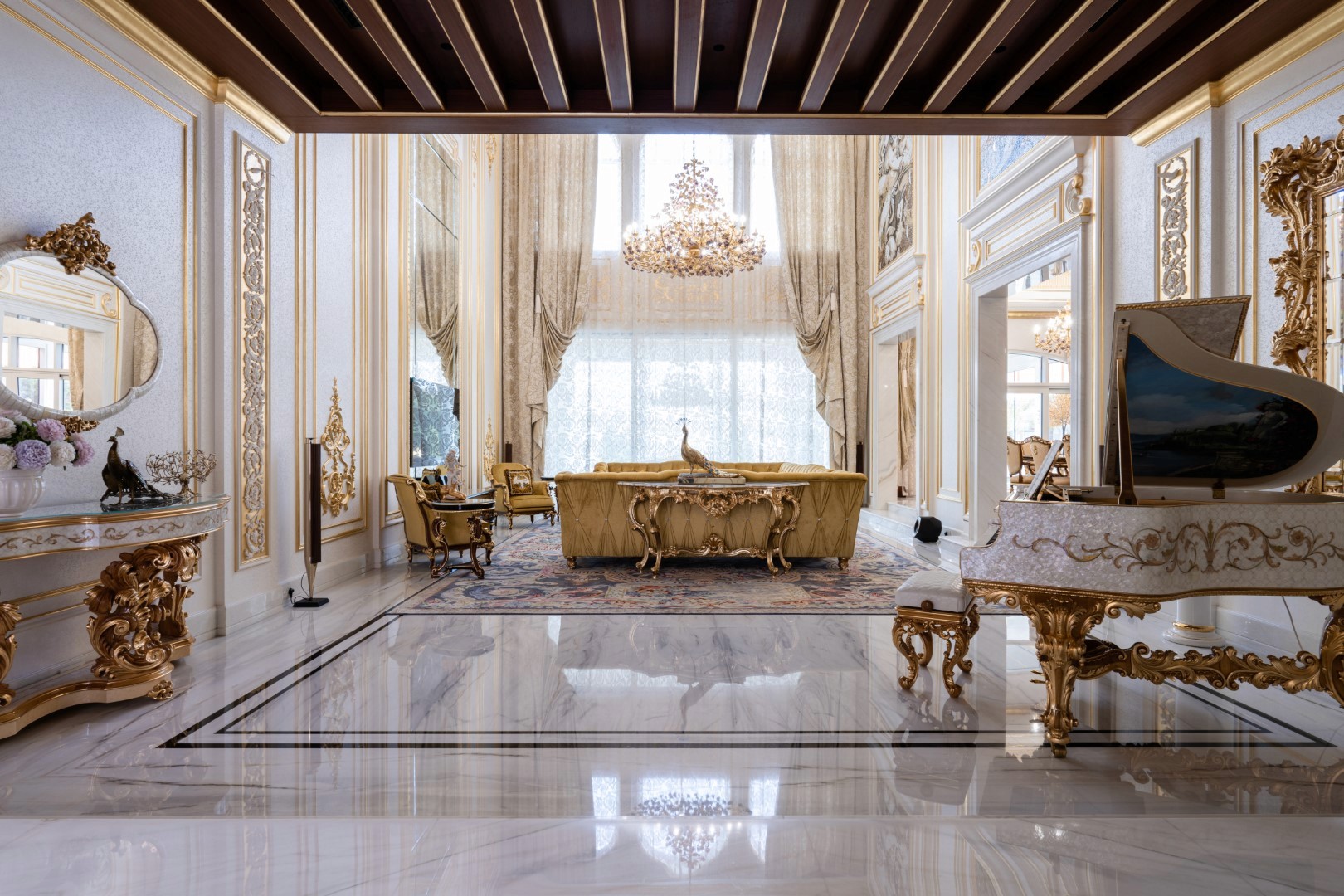 Luxurious, ornately decorated living room with a grand piano, opulent gold-trimmed furniture, a large shimmering chandelier, and expansive windows providing natural light.