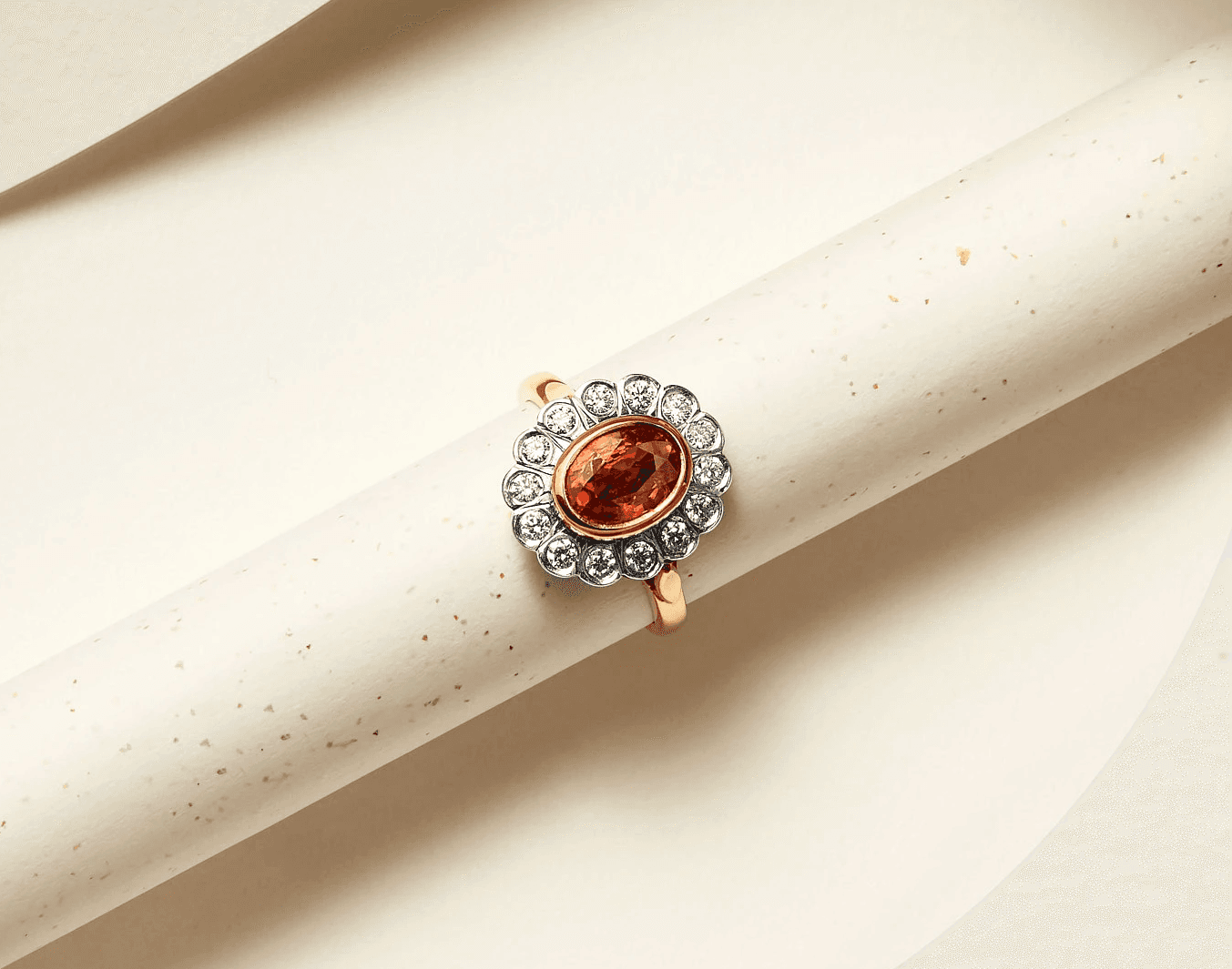 Elegant gemstone and diamond halo ring on textured background.