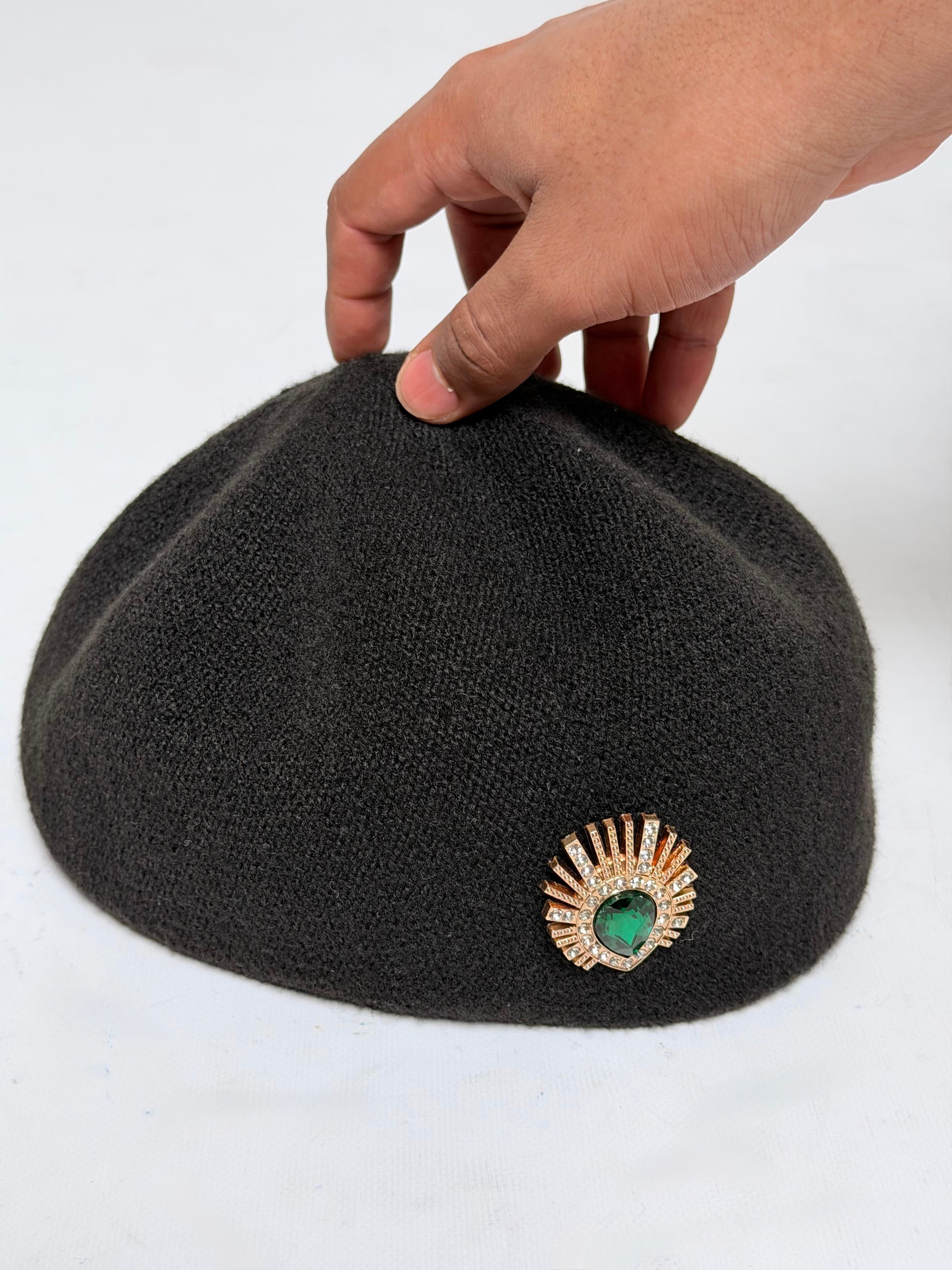 Black wool hat adorned with a decorative brooch.