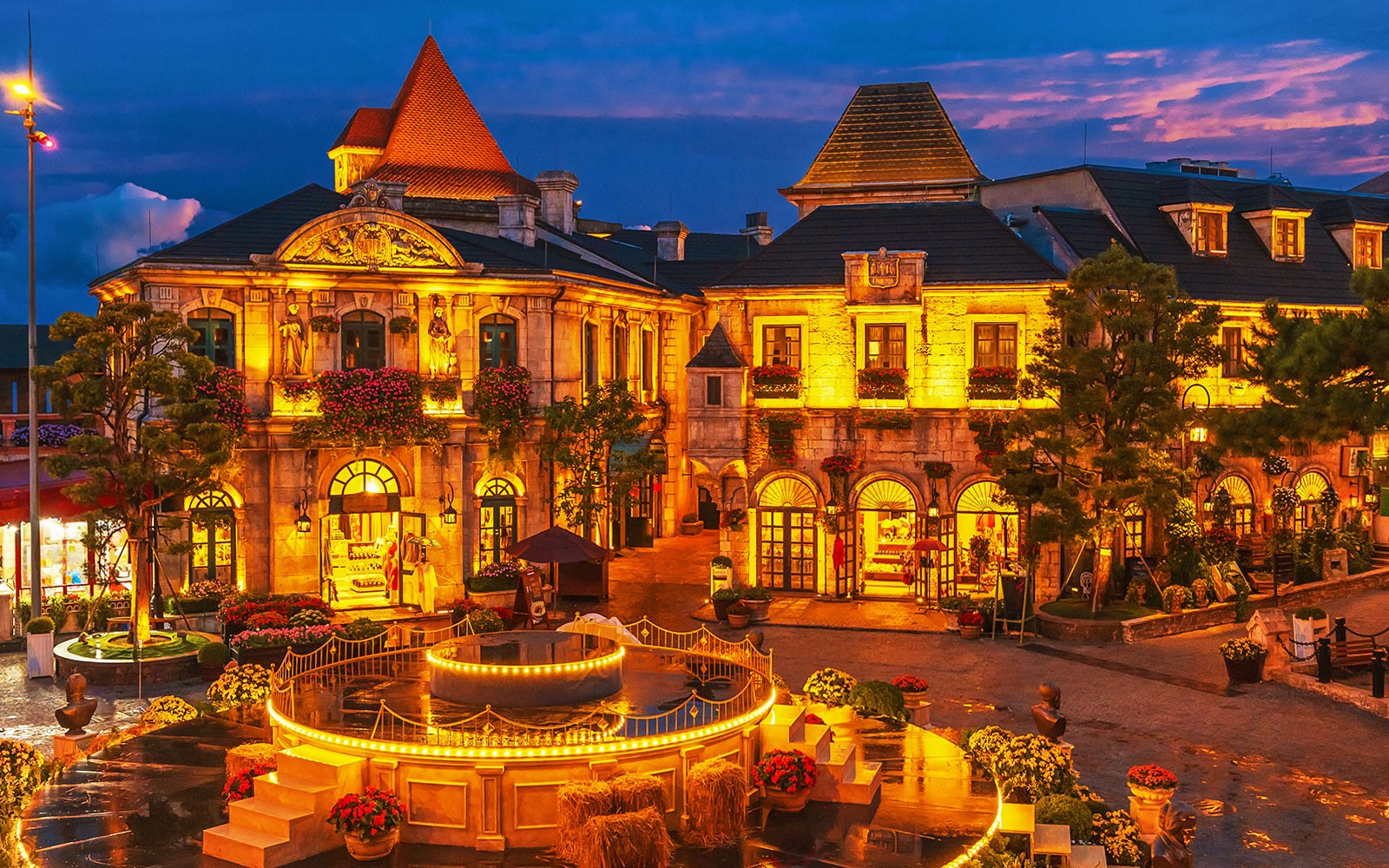 Central square in medieval French village at Ba Na Hills Park, Da Nang, illuminated at dusk.