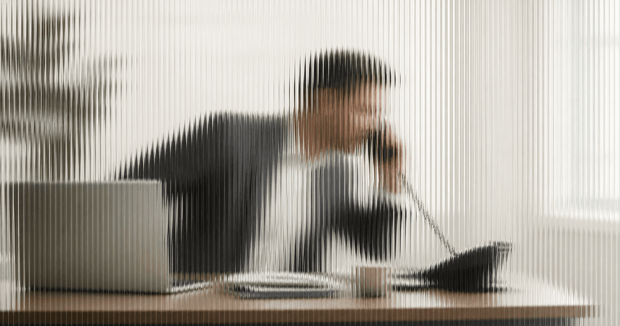 Insurance rep quickly answering a phone call, leaning in for speed-to-lead, seen through vertical fluted glass