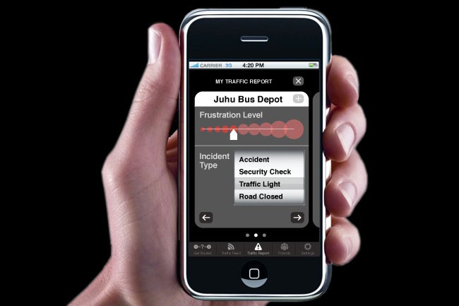 A hand holds a smartphone displaying a traffic report from the Juhu Bus Depot. The screen shows "MY TRAFFIC REPORT" at the top, with "Juhu Bus Depot" as the title. Below it, "Frustration Level" is shown with five red dots, indicating high frustration. The "Incident Type" listed is "Accident," and the "Traffic Light" option is selected. The "Road Closed" option is marked. The bottom of the screen shows standard iPhone navigation buttons, including Home, End, End Call, and Home.