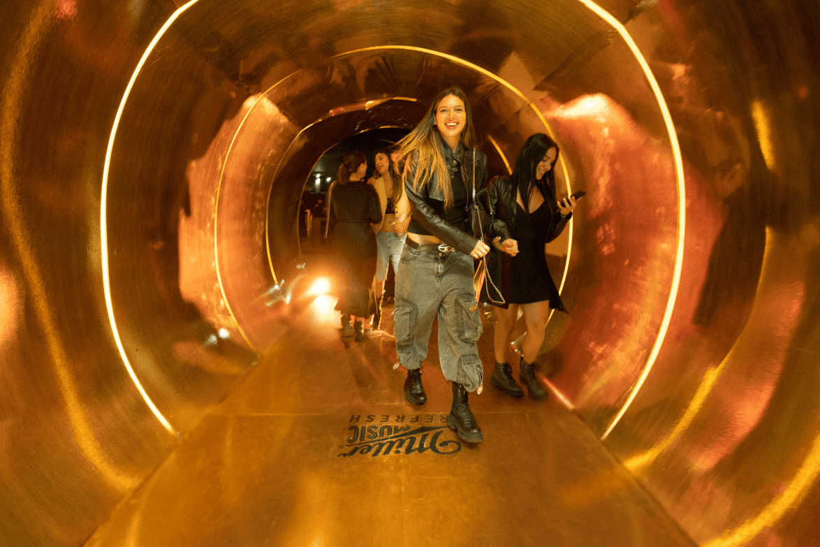 A person walking through a large, golden tunnel with lighting creating a warm glow around them.