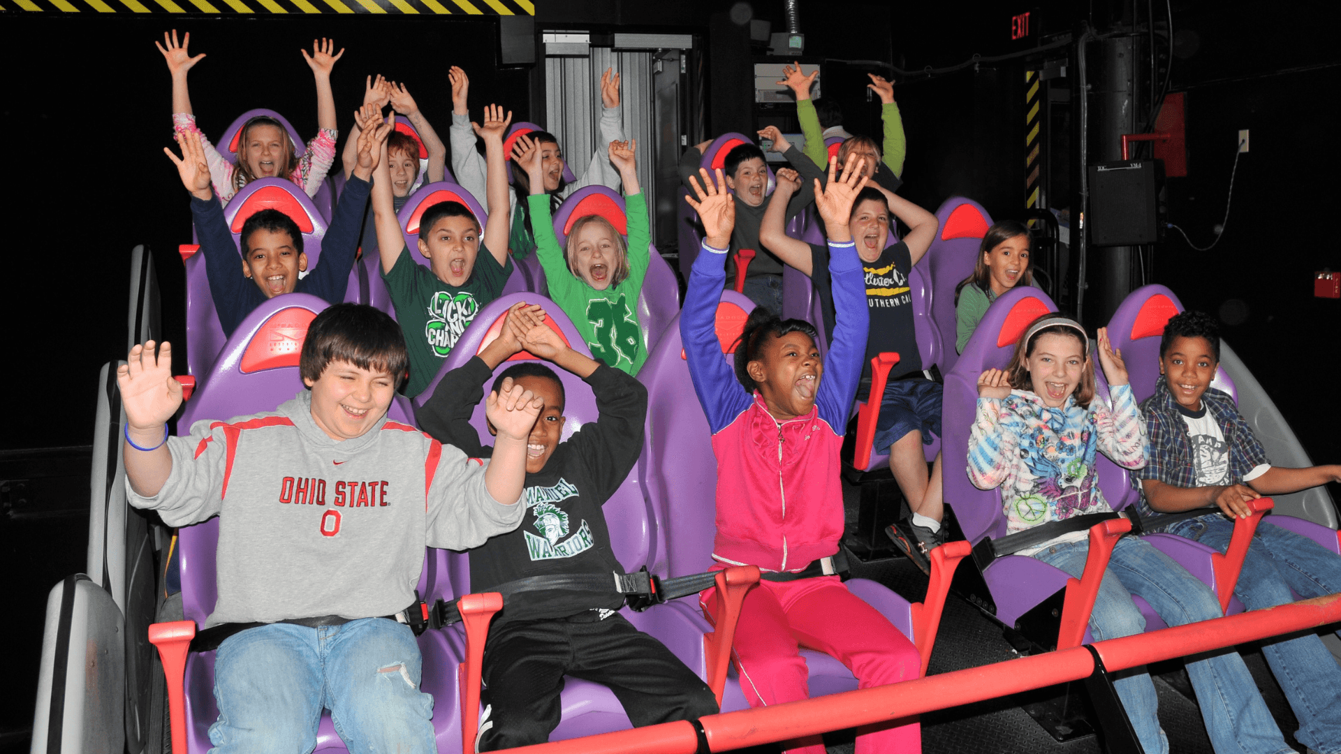 15 kids ride the virtual roller coaster with excited faces.