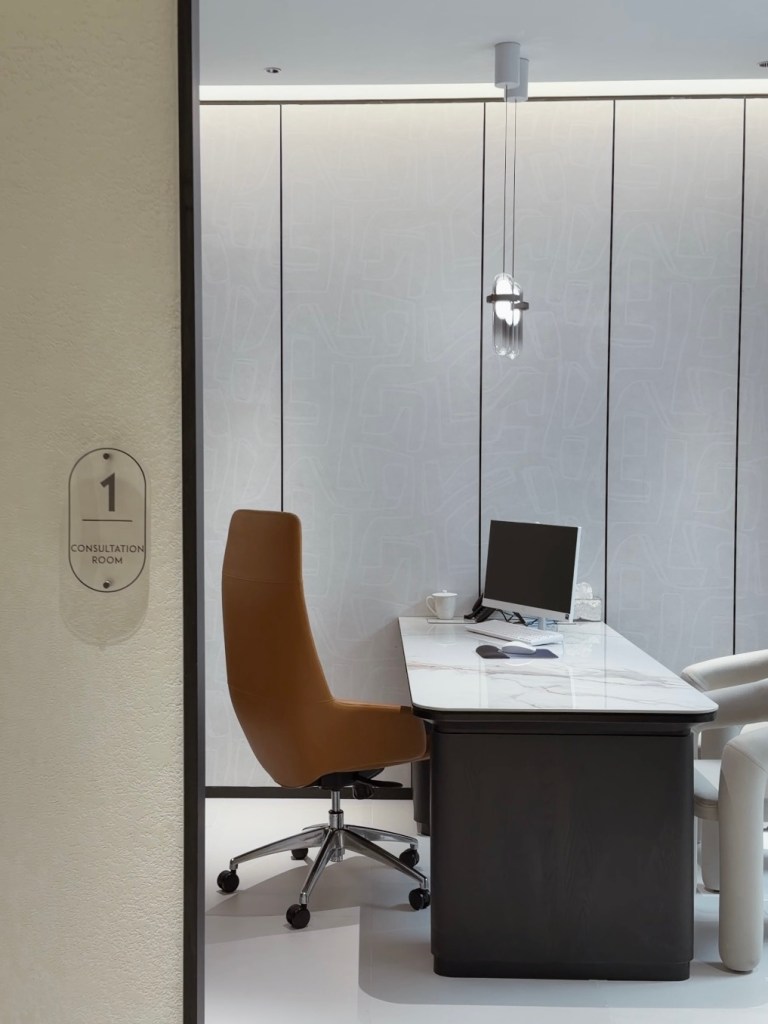 Interior view of a consultation room at Suisse Clinic, featuring a marble desk, ergonomic chair, computer monitor, and soothing decor.