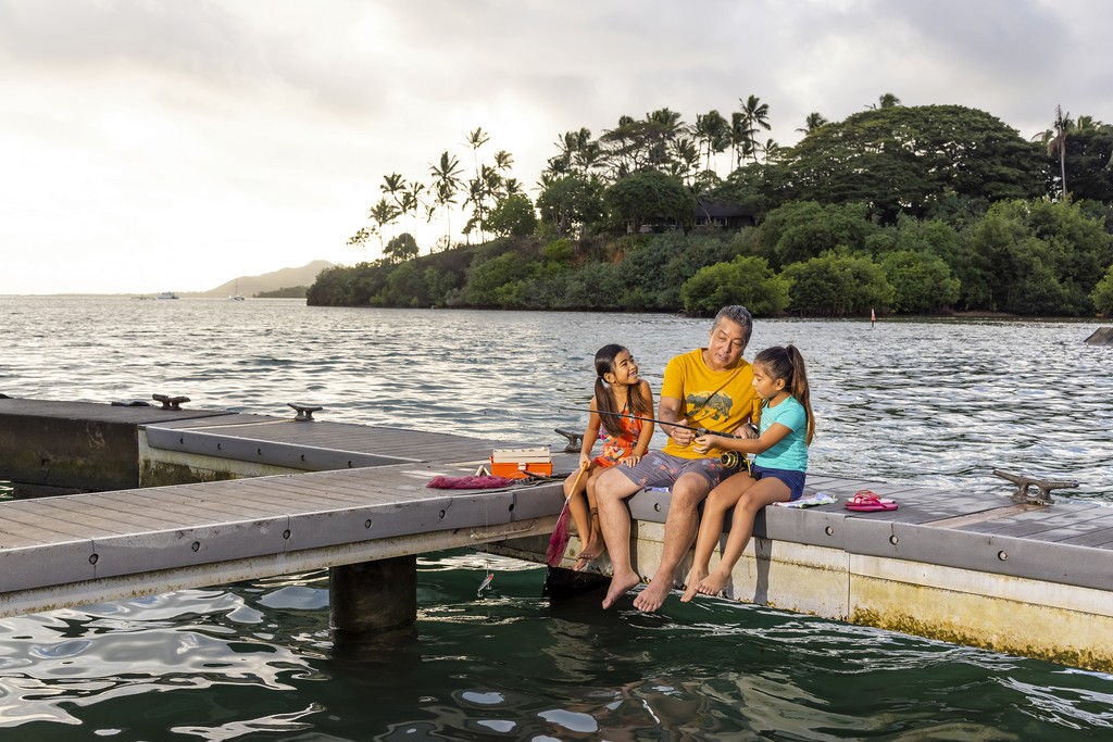 Family sitting near ocean on Hawai‘i shoreline