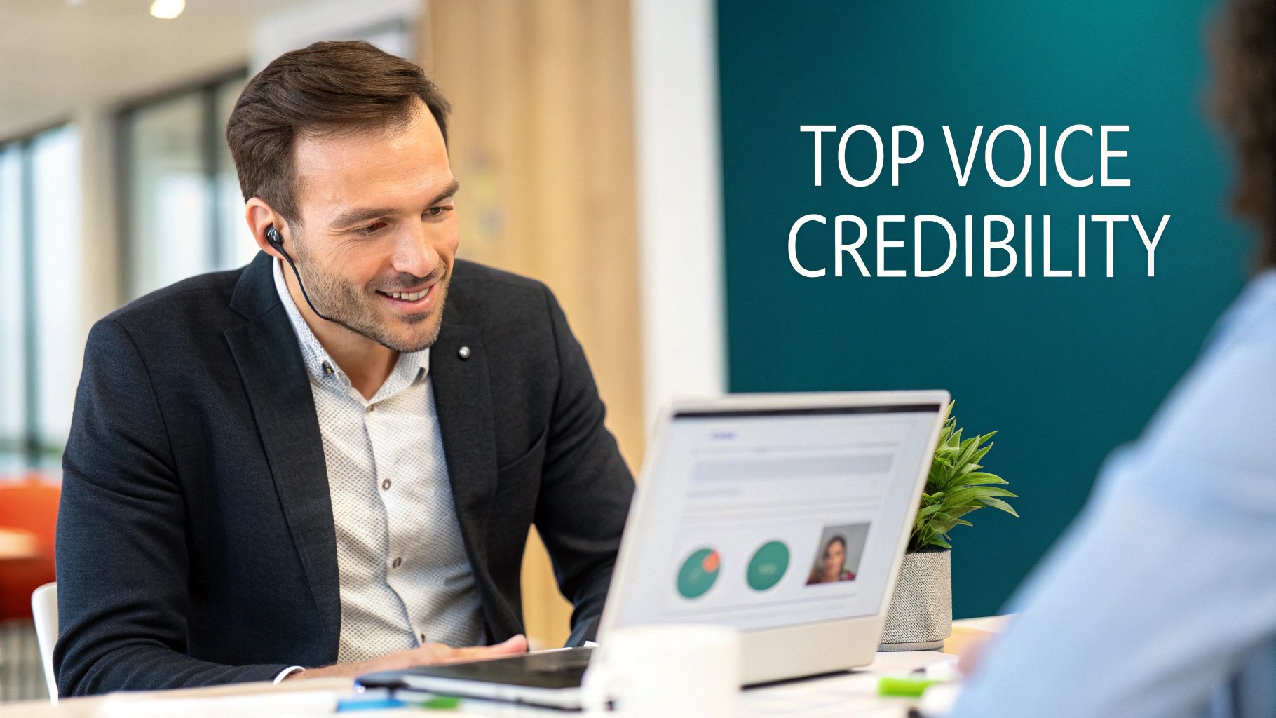 A smiling man wearing an earbud looks at a laptop, with 'TOP VOICE CREDIBILITY' text on the wall.