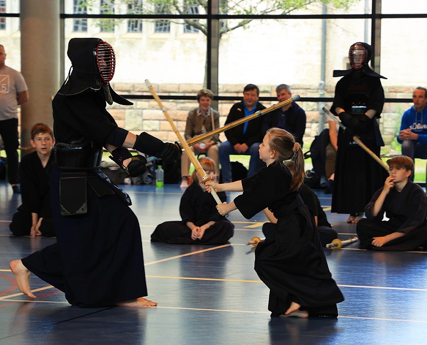Jeunes pratiquants de Kendo s’exerçant au shinai sous le regard de membres du club.