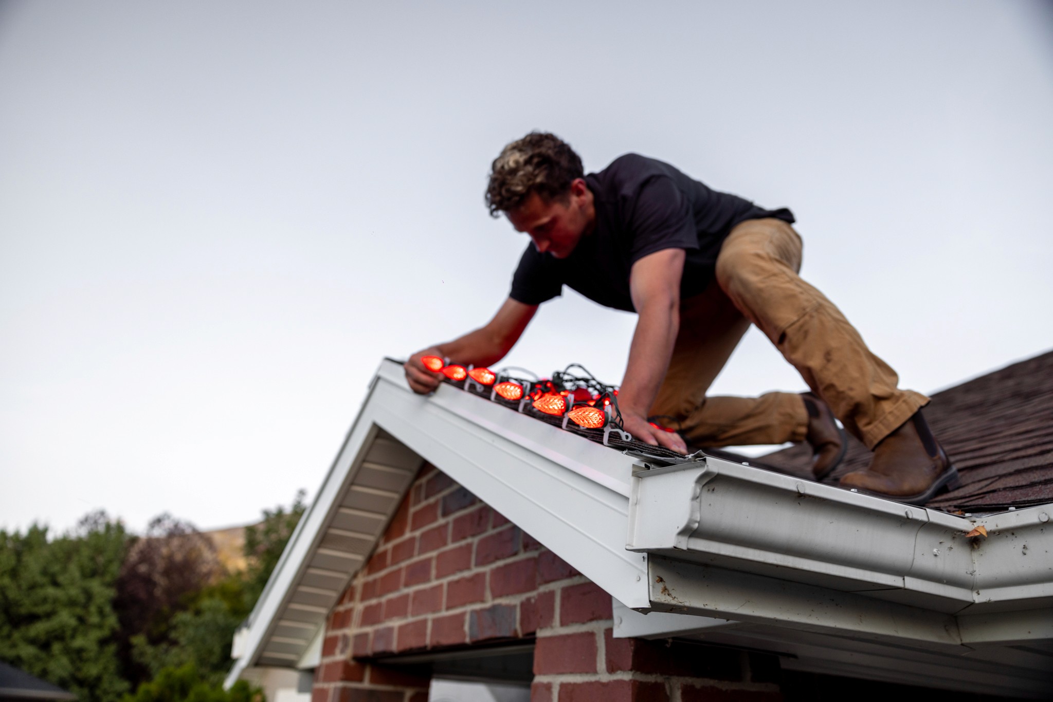 Technicians wrapping roof edges with LED light strands