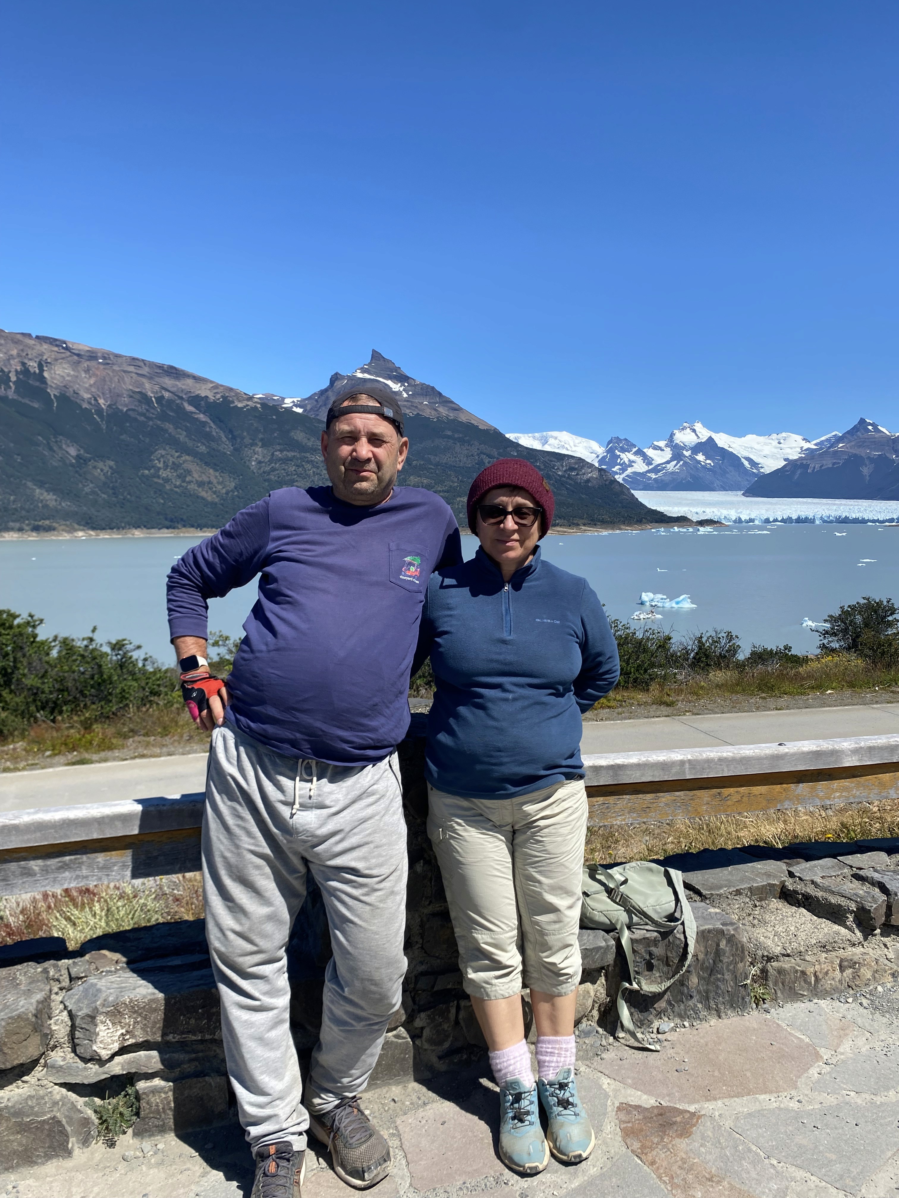 Mujer sentada sobre un tronco frente a una cascada doble en un bosque frondoso de Argentina.