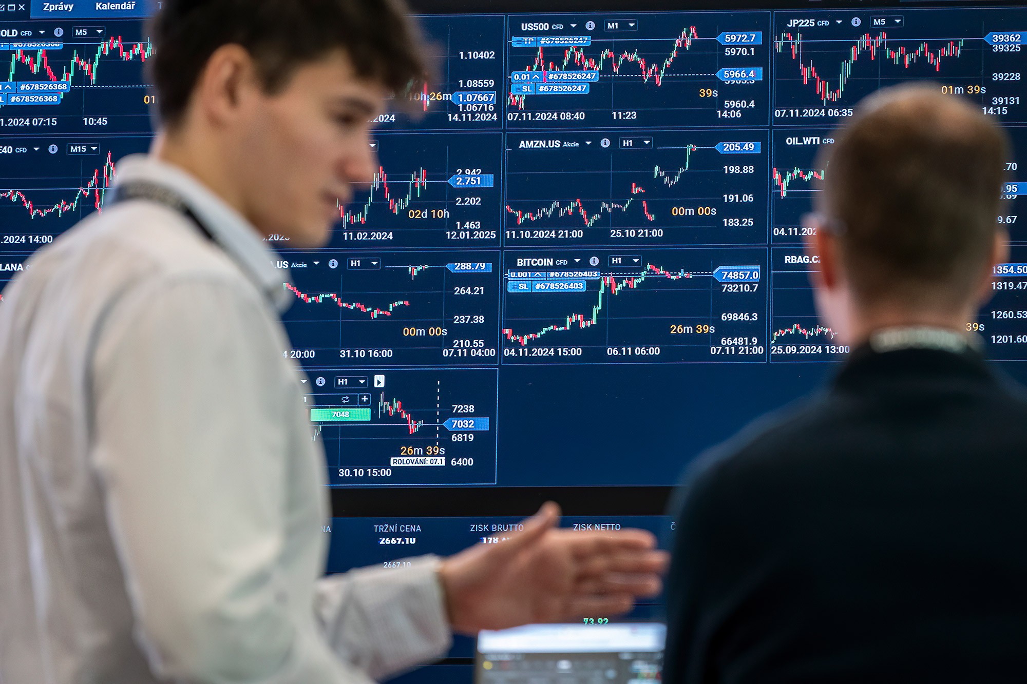 Attendees reviewing live financial market charts and trading data at Money Maker conference in Prague