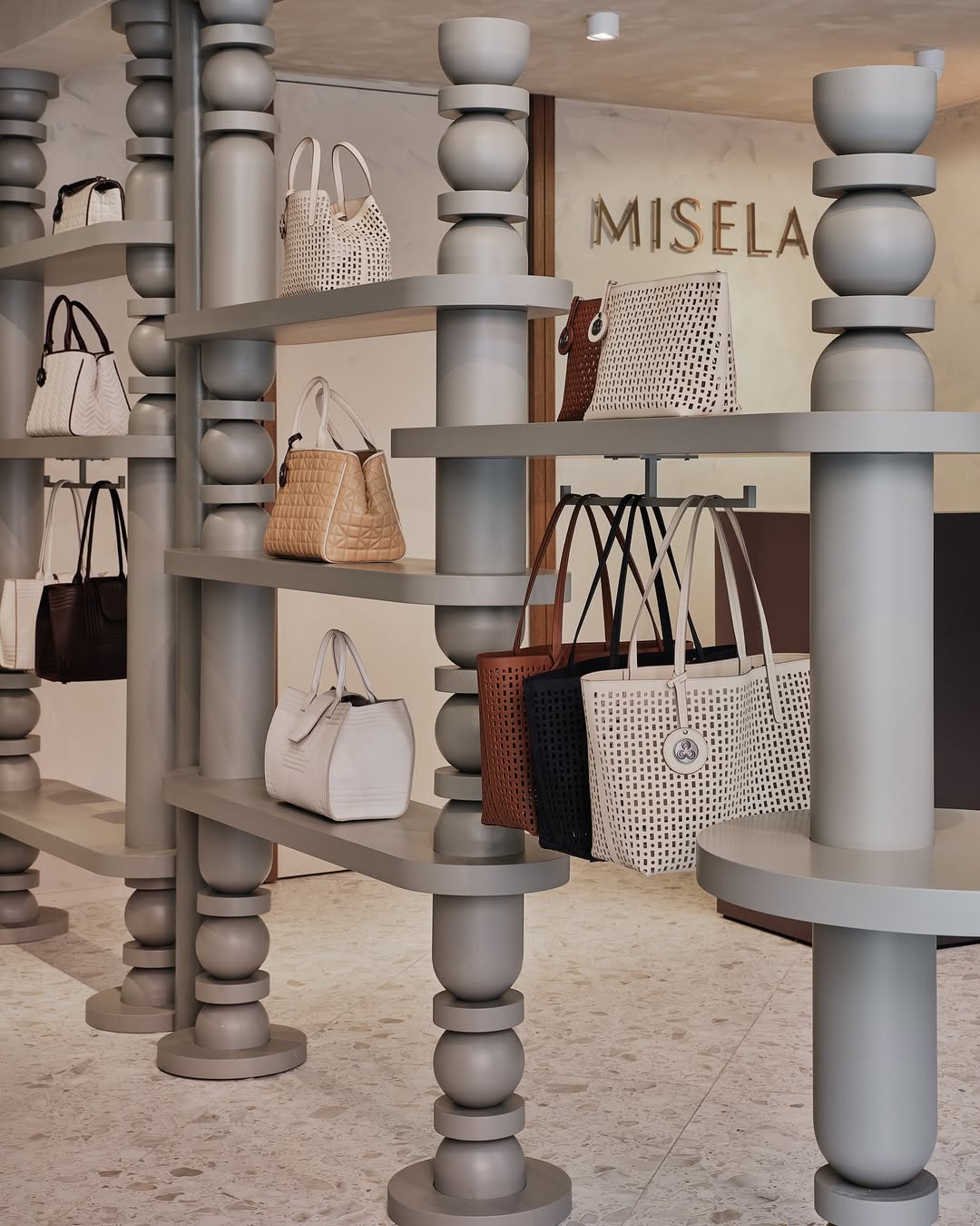 Handbag display inside Misela New York store with sculptural shelving and dimensional Misela wall logo.
